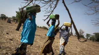 Frauen beim Wasserholen im ländlichen Burkina Faso Drei Frauen tragen Wasserbehälter
