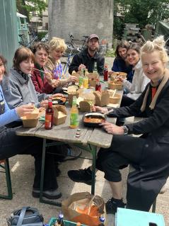 Mehrere junge Menschen sitzen sich auf Bänken an einem Aufklapptisch gegenüber und essen gemeinsam.