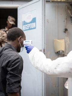 Ein medizinischer Mitarbeiter misst am 19. Mai 2026 in Goma in der Demokratischen Republik Kongo im Rahmen der Untersuchungen auf Ebola die Temperatur eines Einwohners. Eine Person in medizinischer Schutzausrüstung misst die Temperatur einer zweiten Person. Im Hintergrund stehen zwei Personen in Militäruniform.
