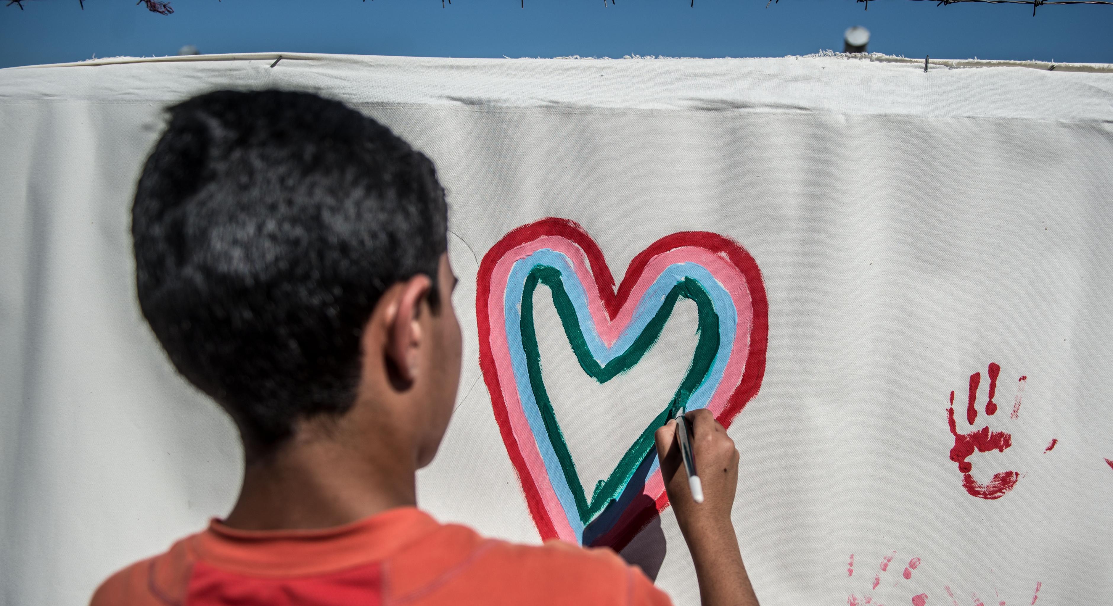 Ein irakischer Junge malt ein Herz auf eine Leinwand
