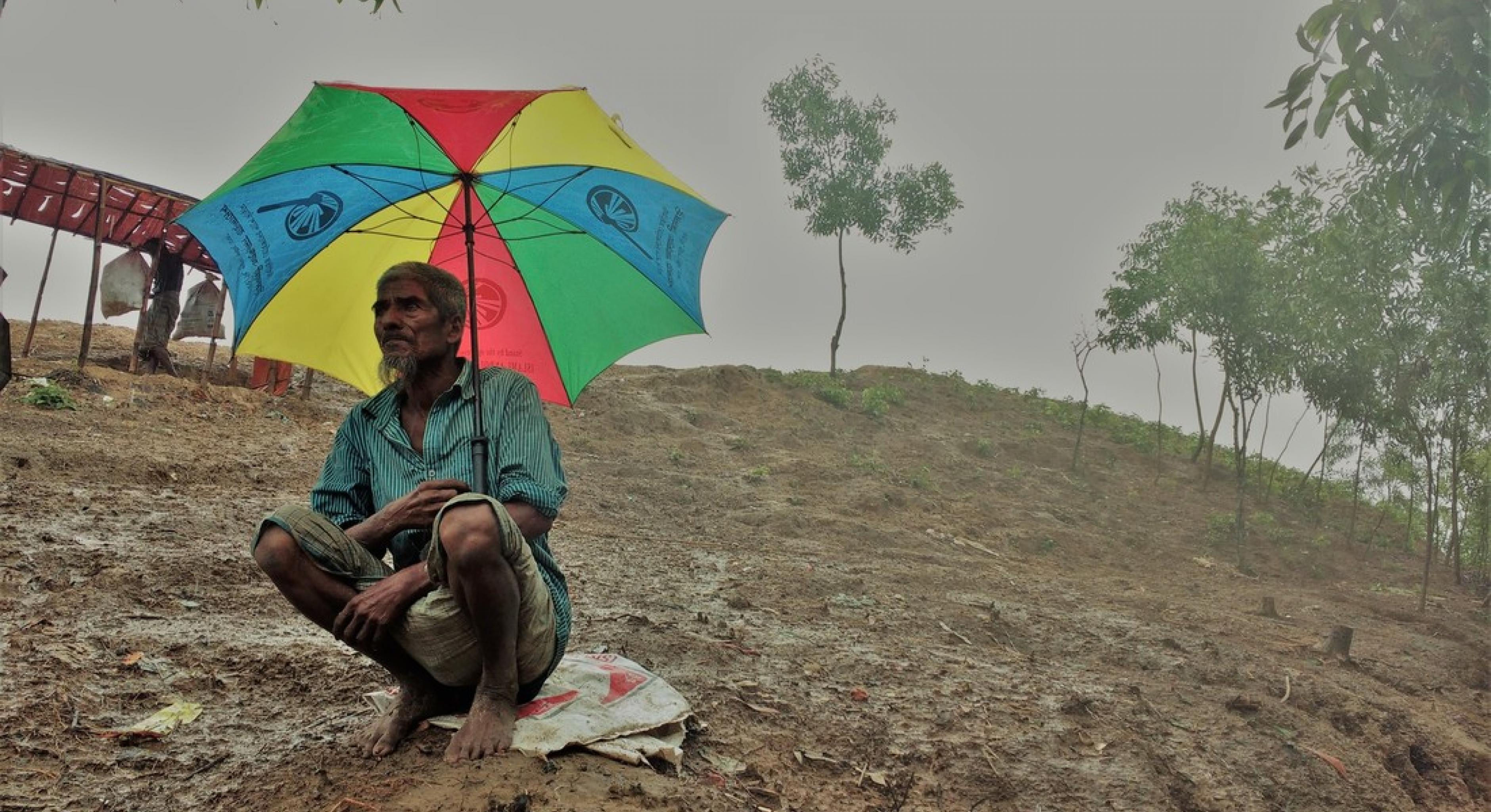 Rohingya-Mann mit Regenschirm auf Hügel