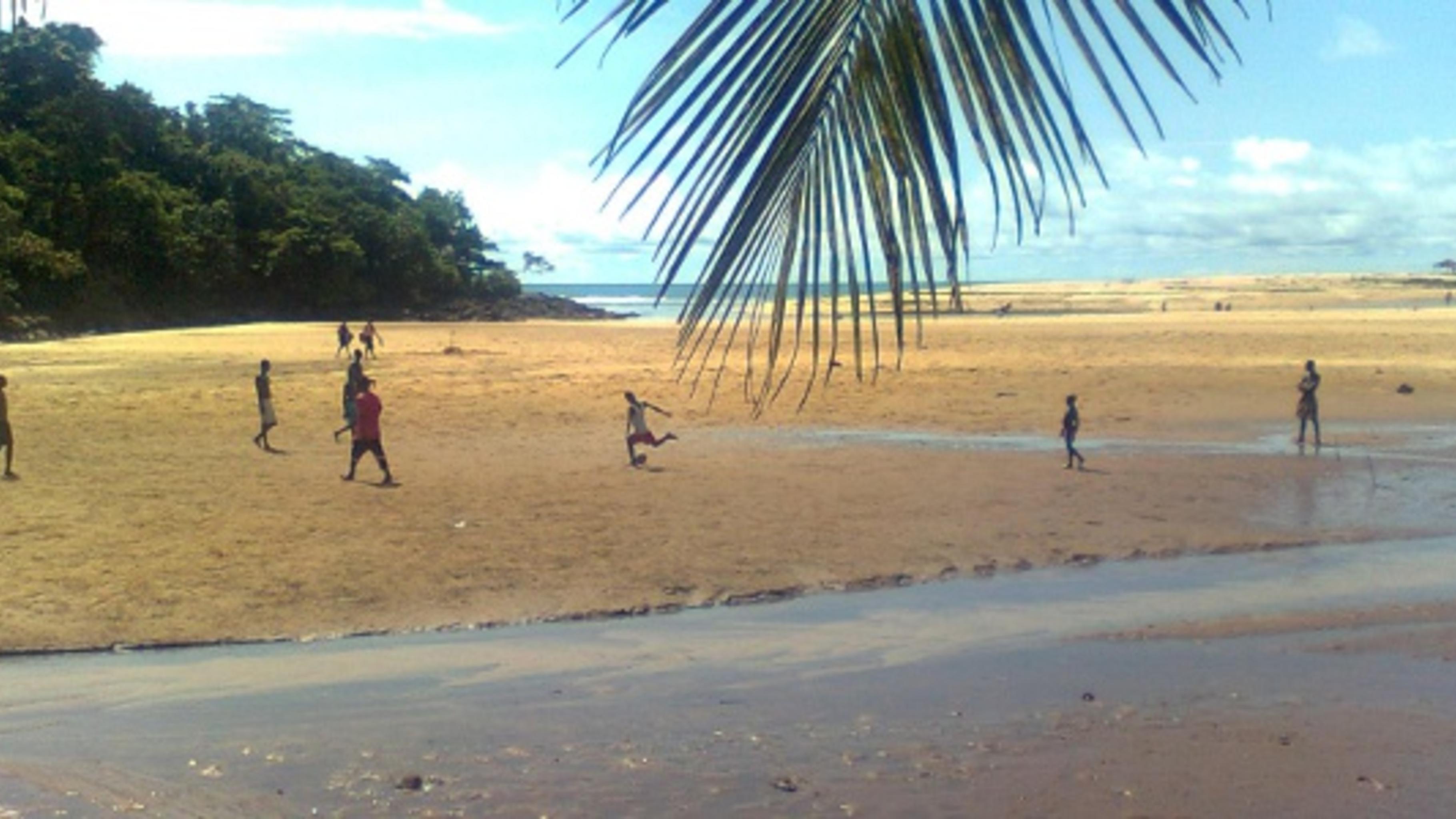 Foto: Jungen spielen Fußball an einem Strand.