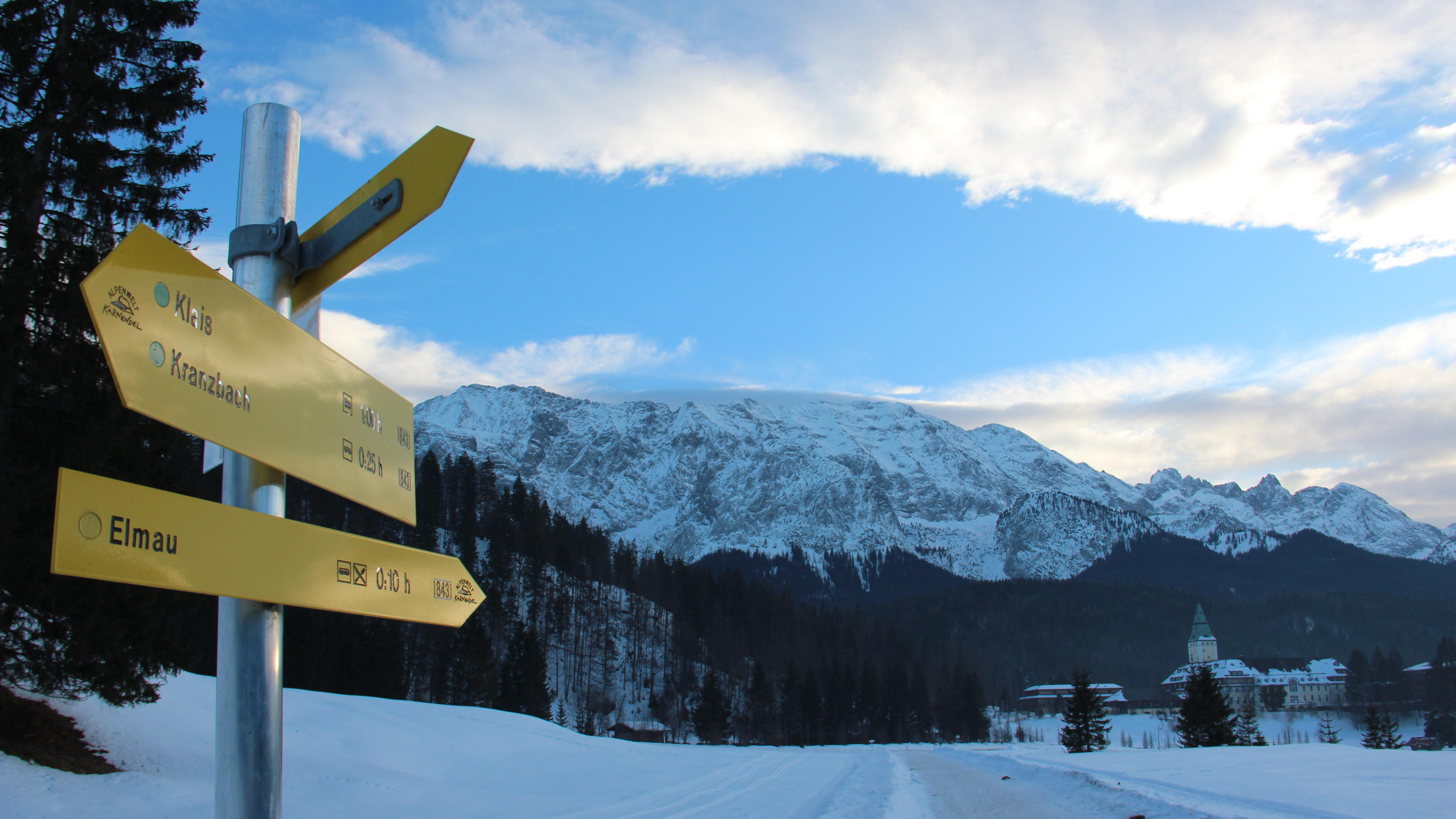 Wegweiser nach Elmau in einer schneebedeckten Alpenlandschaft
