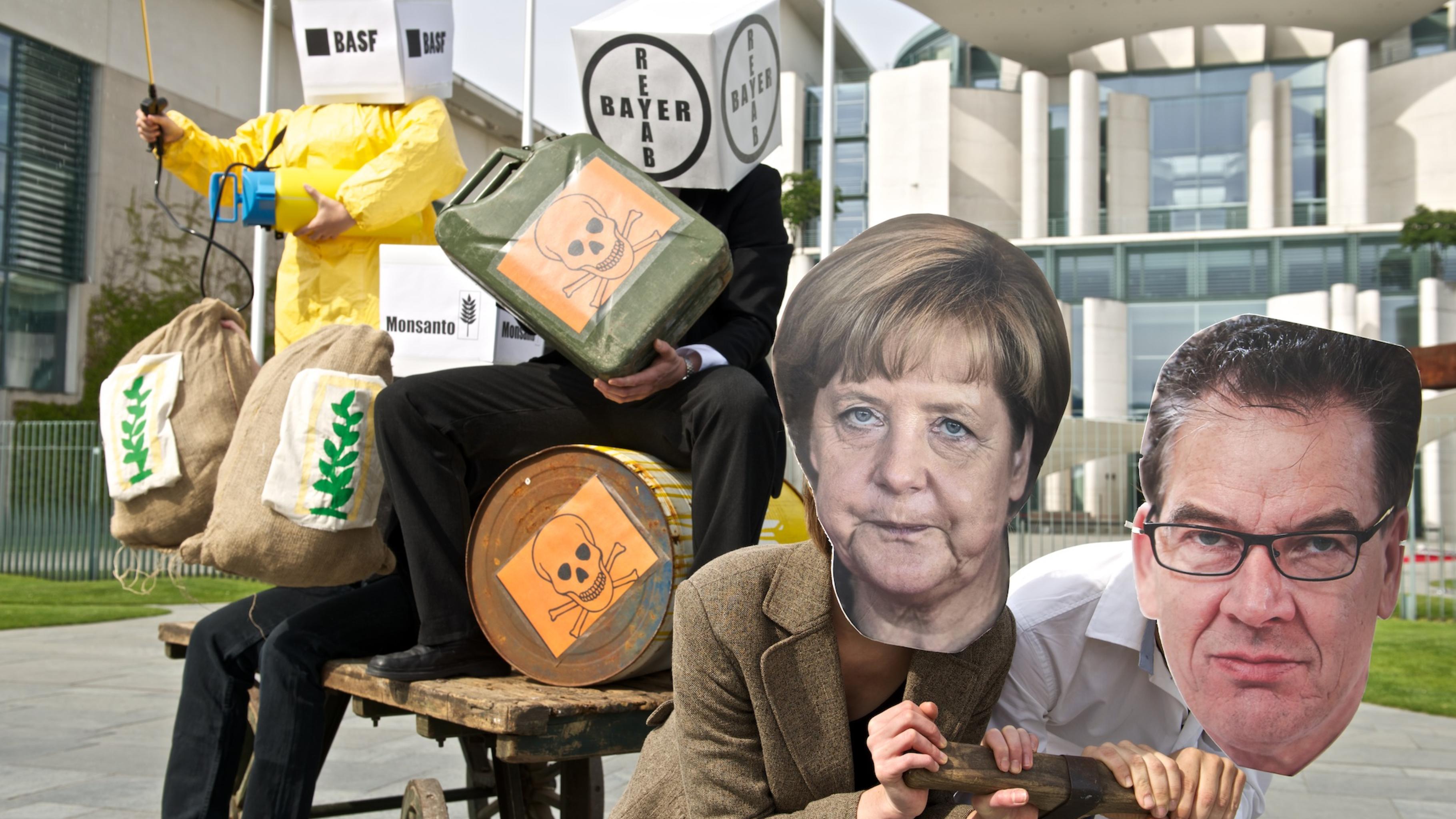 Bundeskanzlerin Angela Merkel und Entwicklungsminister Gerd Müller vor den Karren der Agrarkonzerne Bayer, BASF, Monsanto und Co. gespannt.