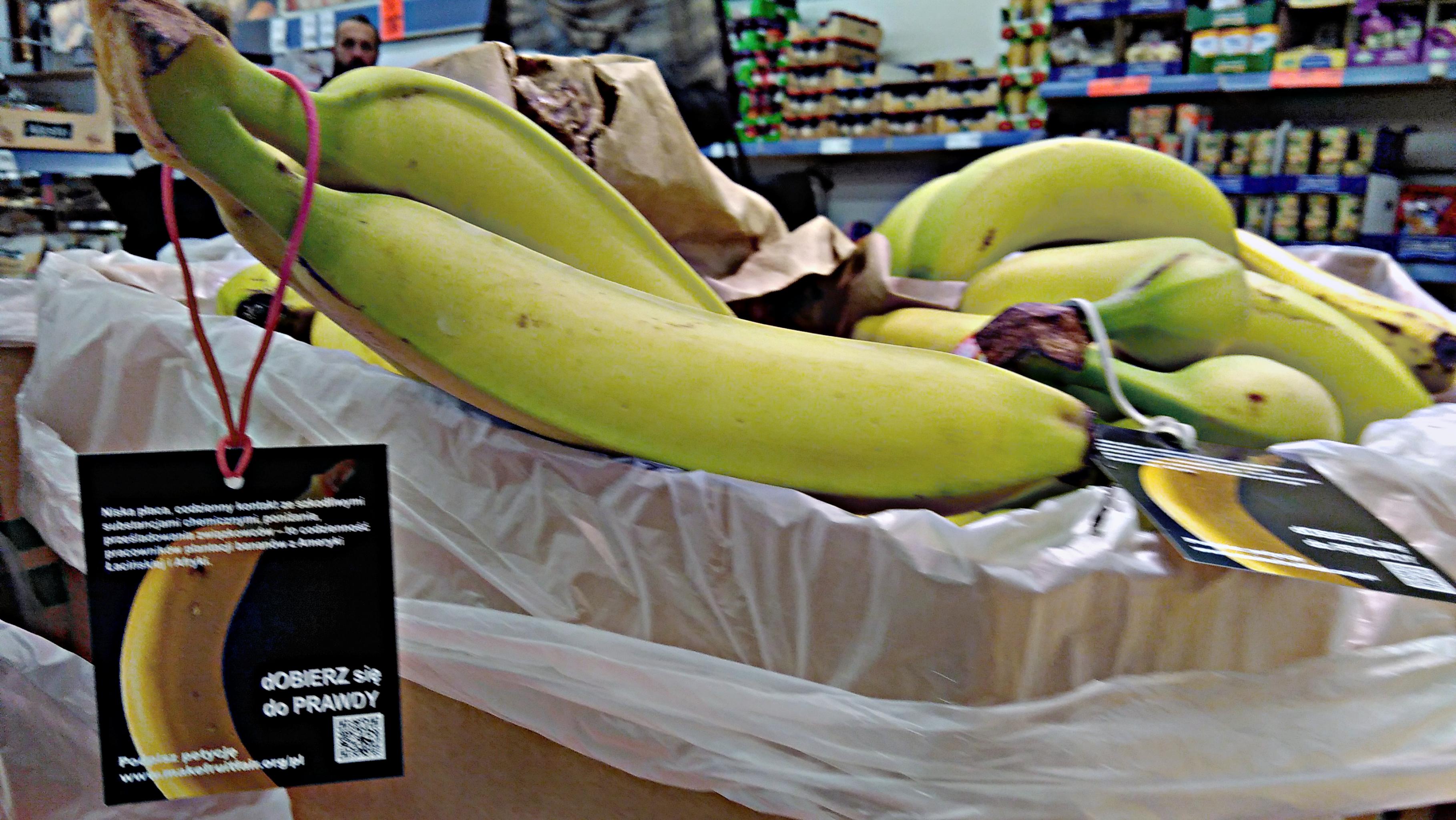 Anhänger mit Informationszetteln hängen an Bananen in Kisten im Supermarkt