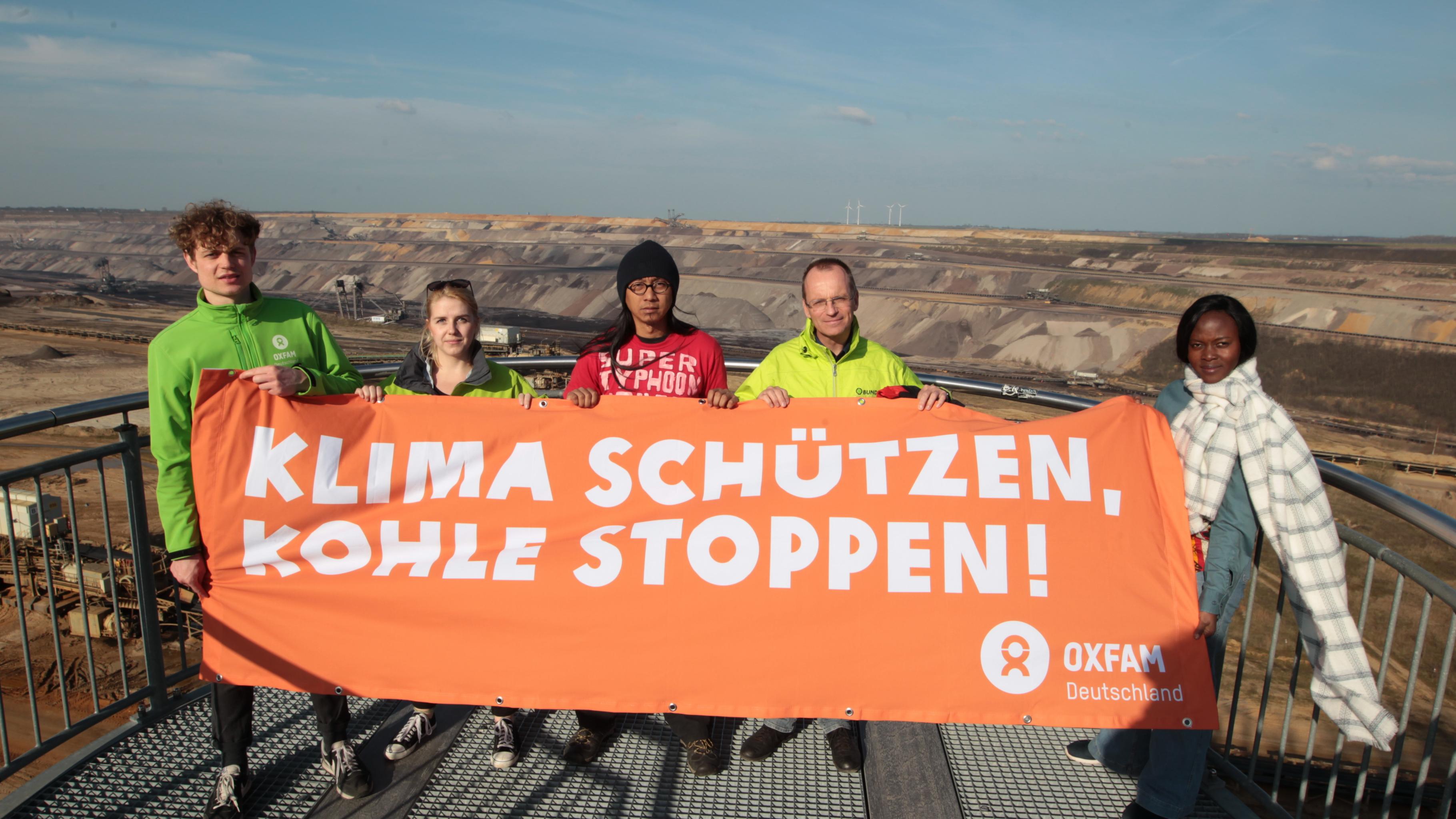 Klimazeug/innen und Vetreter/innen von Oxfam und BUND fordern mit einem Transparent vor dem Braunkohlebau Garzweiler „Klima schützen, Kohle stoppen!”