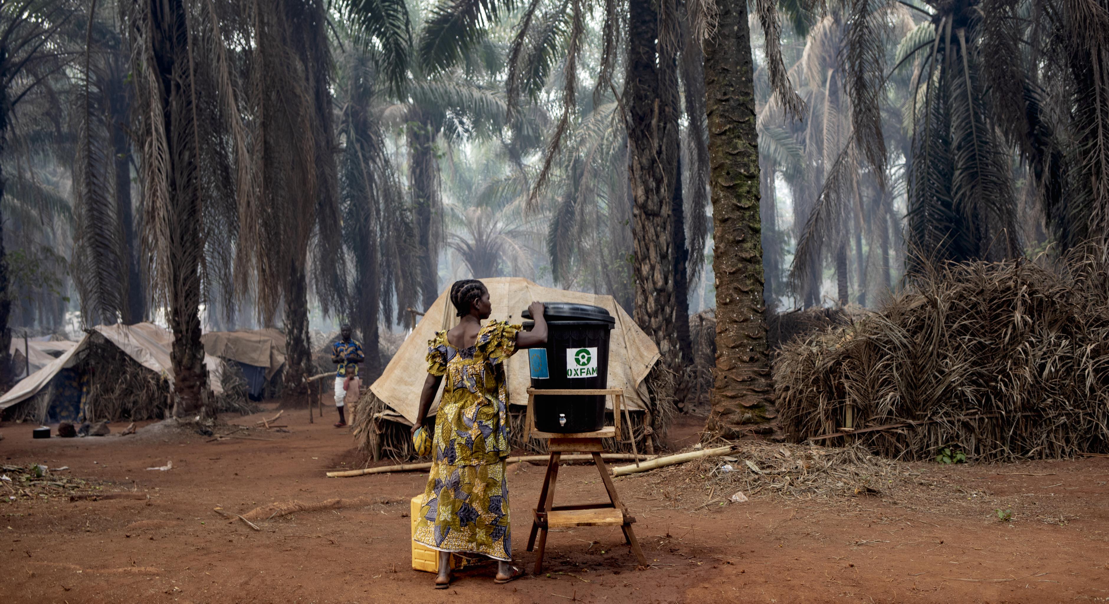 Marcelline Ngoumbeti befüllt eine Handwasch-Station vor dem Dorf Cesacoba (ZAR)