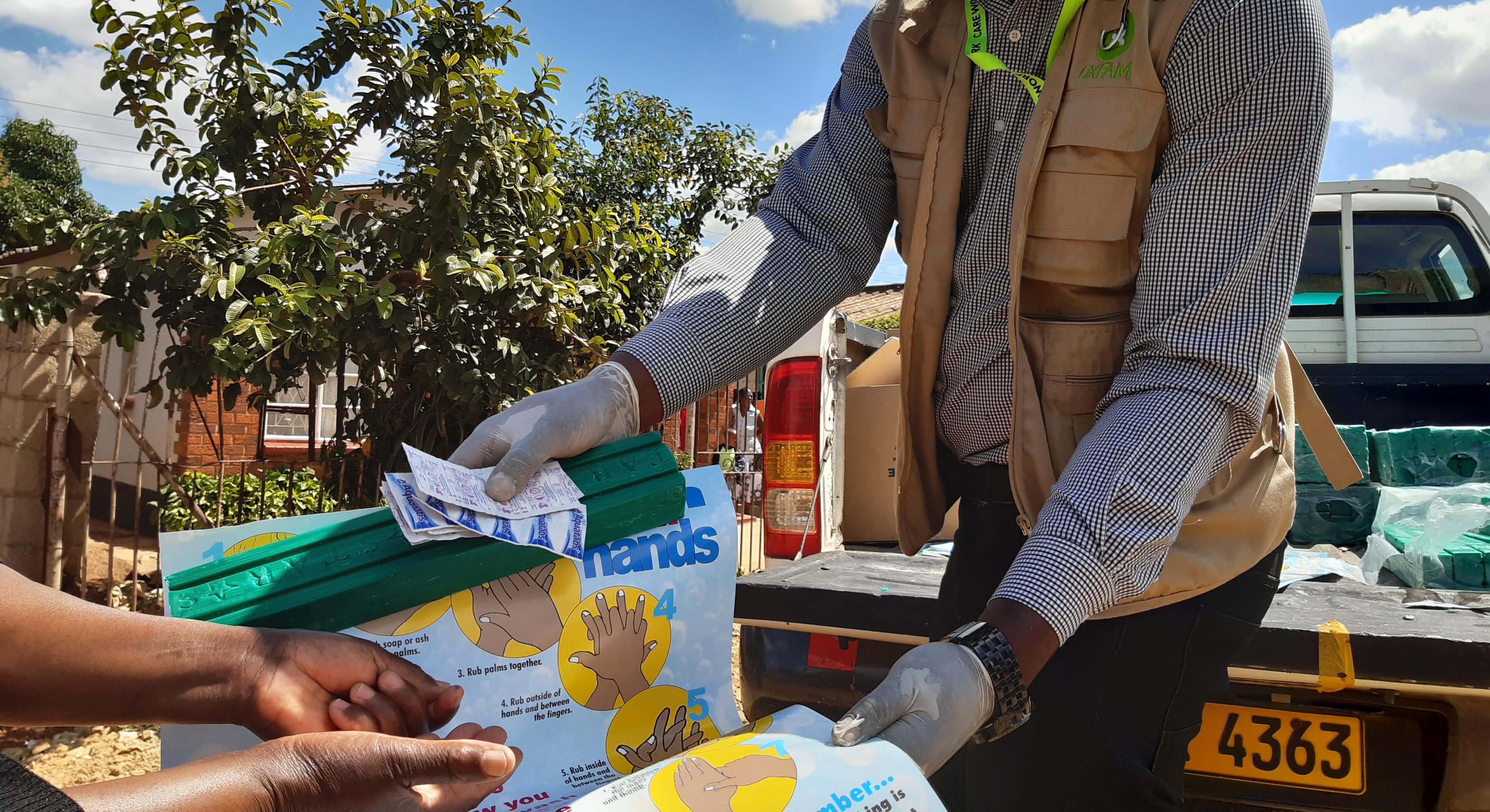 Oxfam-Mitarbeiter Munashe erklärt der Gemeinschaft in Harare, Simbabwe die Nutzung und Verwendung von Aqua-Tabs zur Wasseraufbereitung.