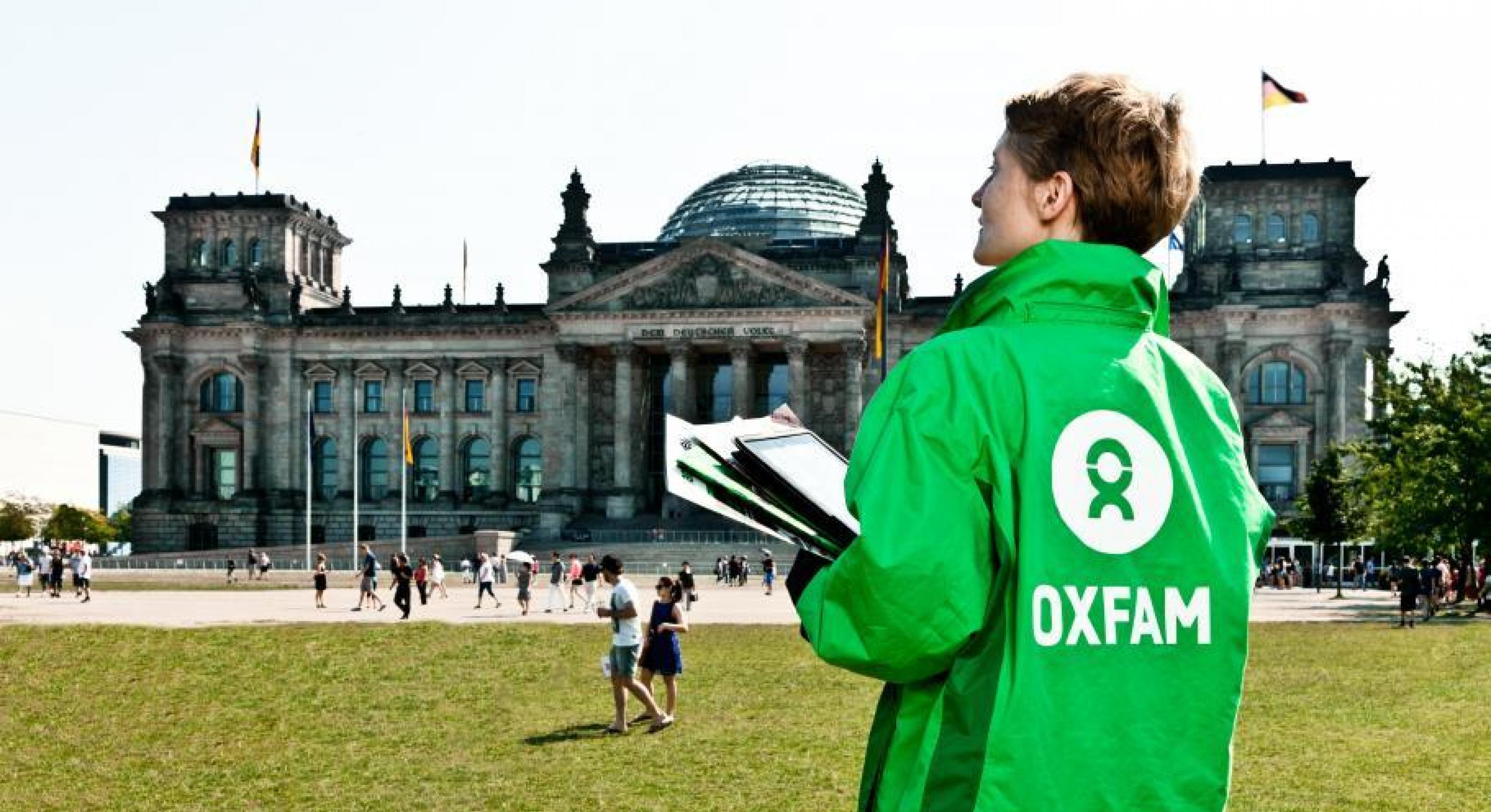 Eine Oxfam Mitarbeiterin steht mit Unterschriftenlisten vor dem Reichstagsgebäude in Berlin. 