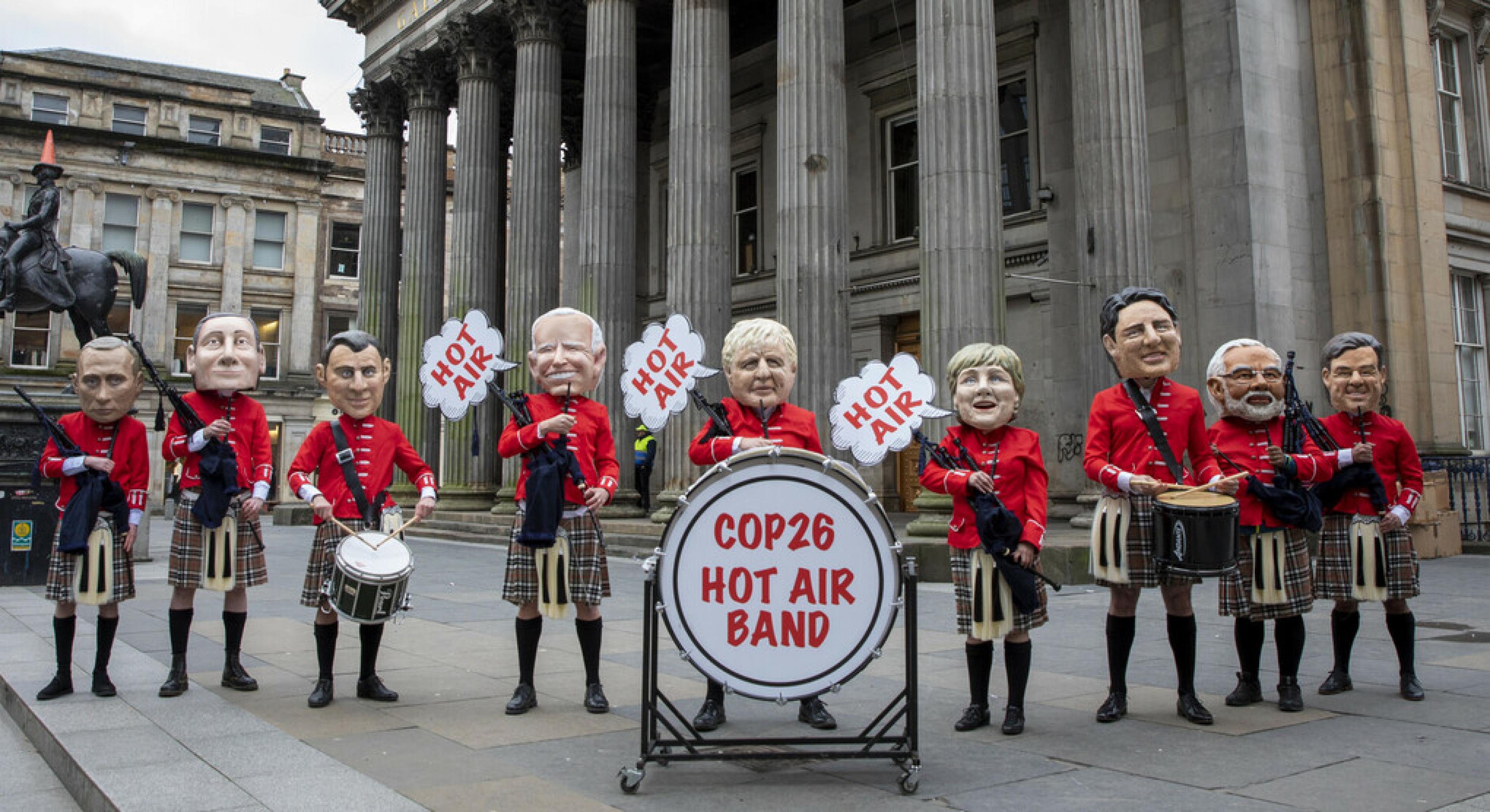 Figuren verschiedener Staatschef*innen posieren als „Hot Air Band“ („Heiße-Luft-Kapelle“). Sie tragen schottische Trachten und halten Dudelsäcke und Trommeln.