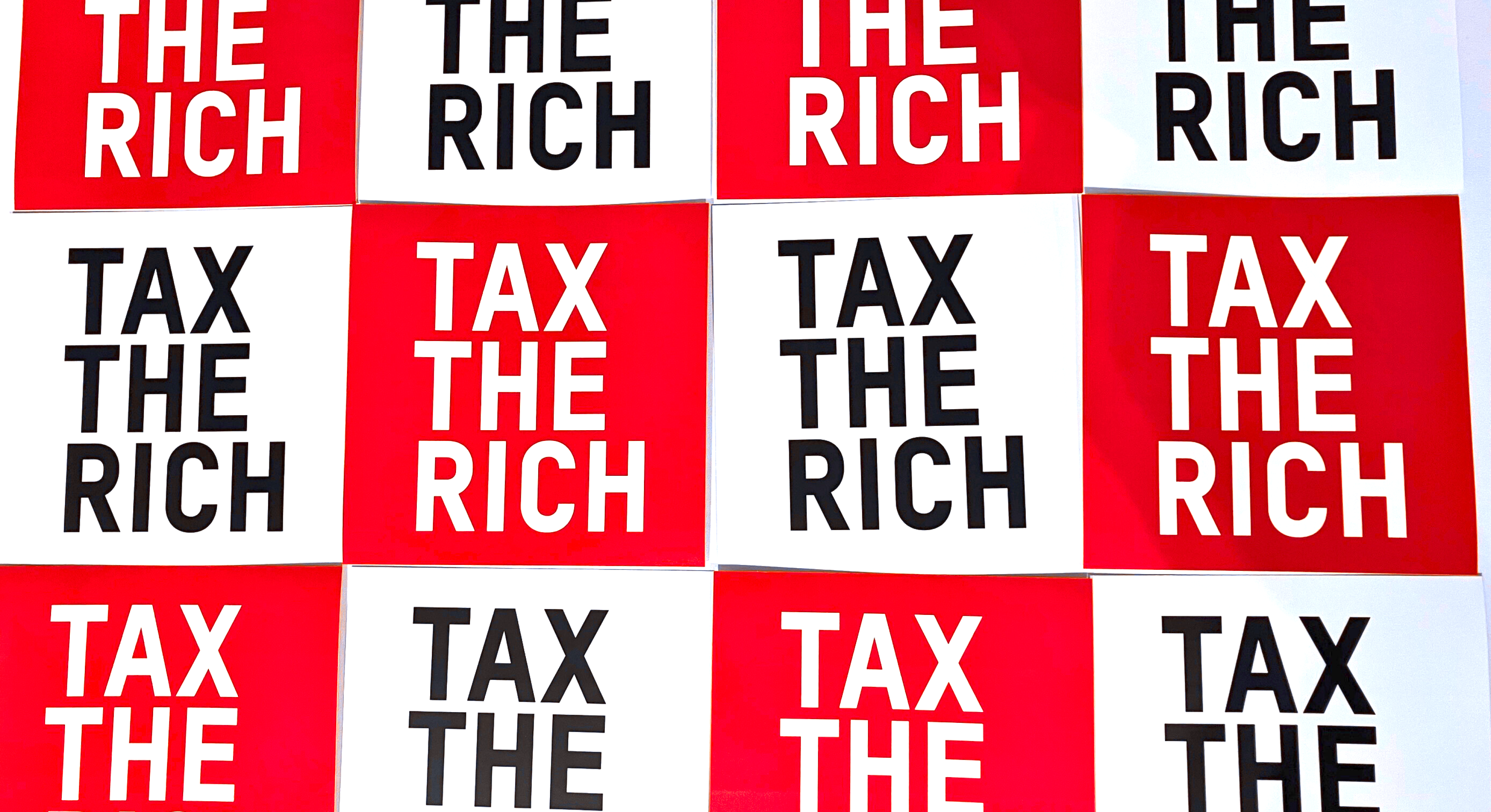 Ein Bild mit der Aufschrift "Tax the Rich" auf einem Schachmuster in rot und weiß.