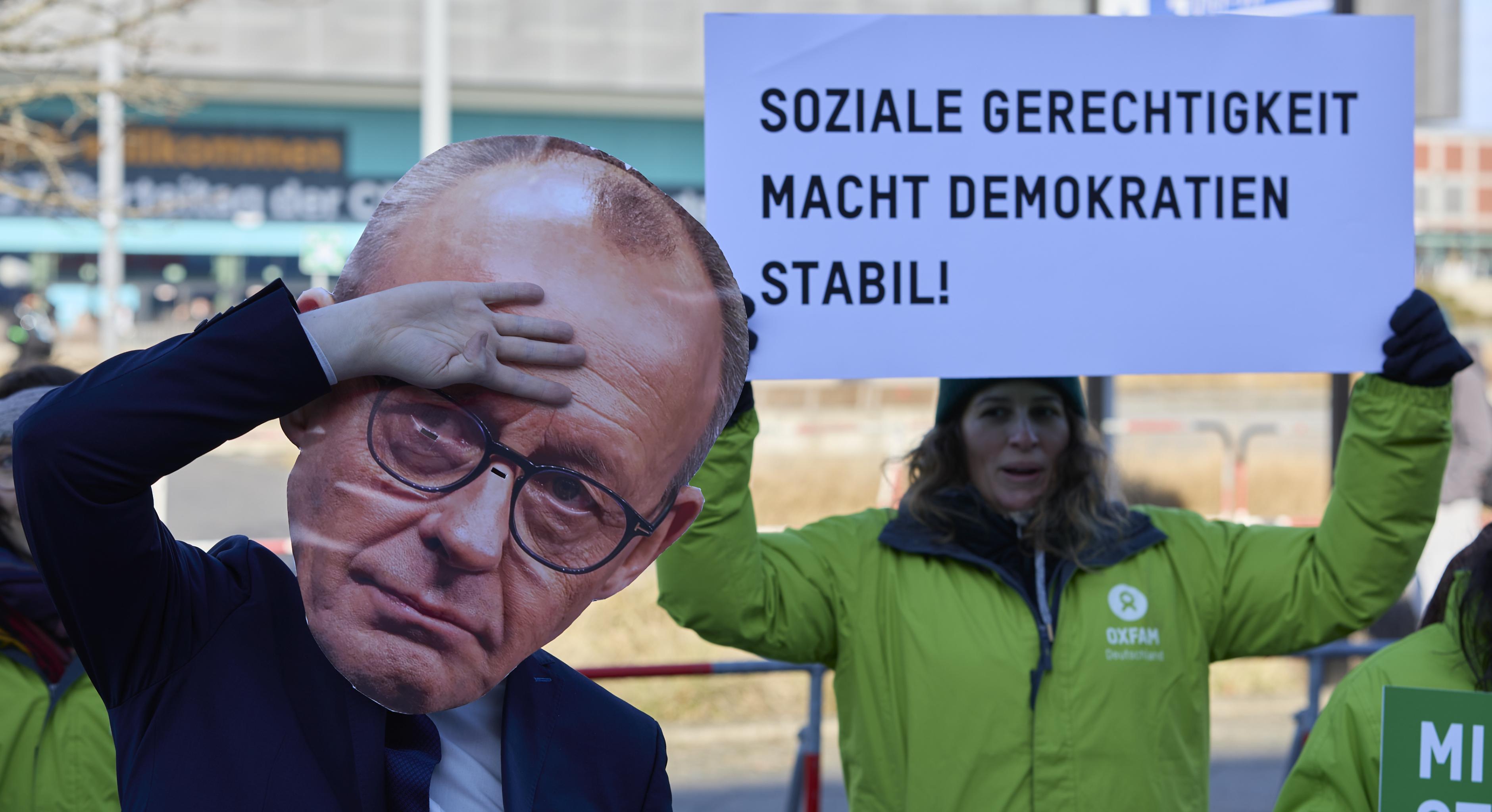 Eine Frau hält ein Schild in die Kamera auf dem zu lesen ist: Soziale Gerechtigkeit macht Demokratien stabil!