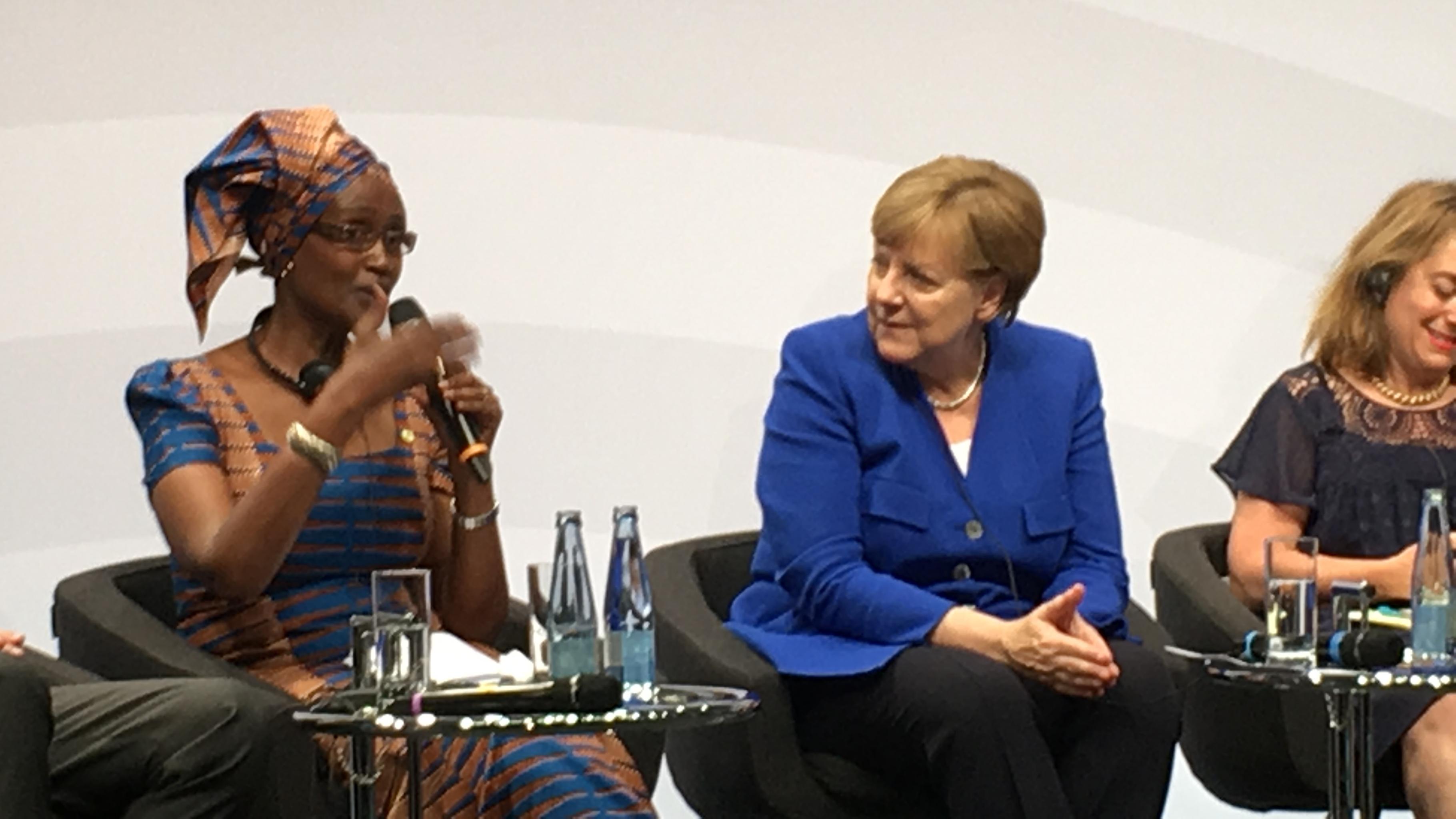 Winnie Byanyima spricht neben Angela Merkel bei einer Podiumsdiskussion.