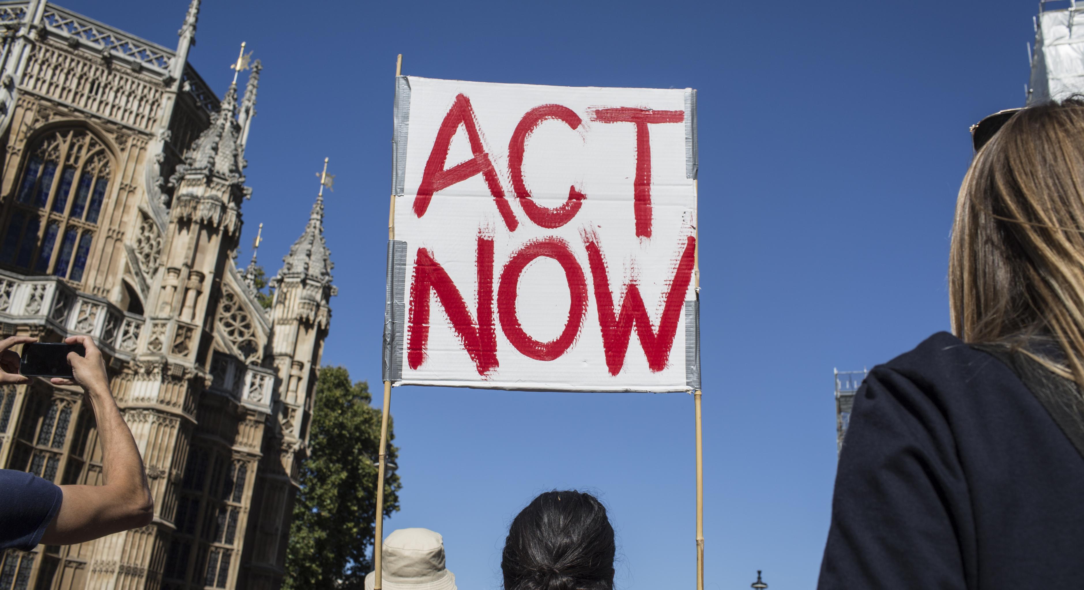 Ein Klimaschild "Act Now" auf einem Klimaprotest in London