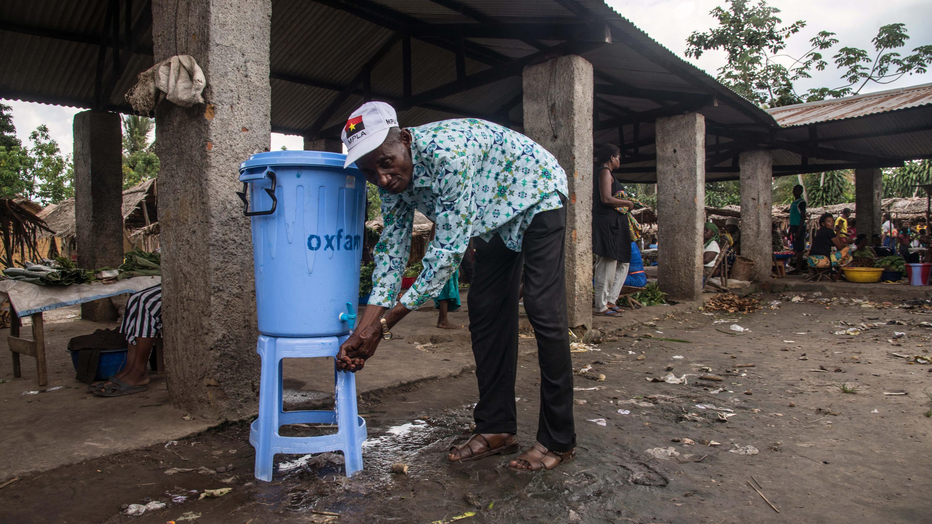 Ein Mann wäscht sich die Hände an einer Oxfam-Wasserstelle.