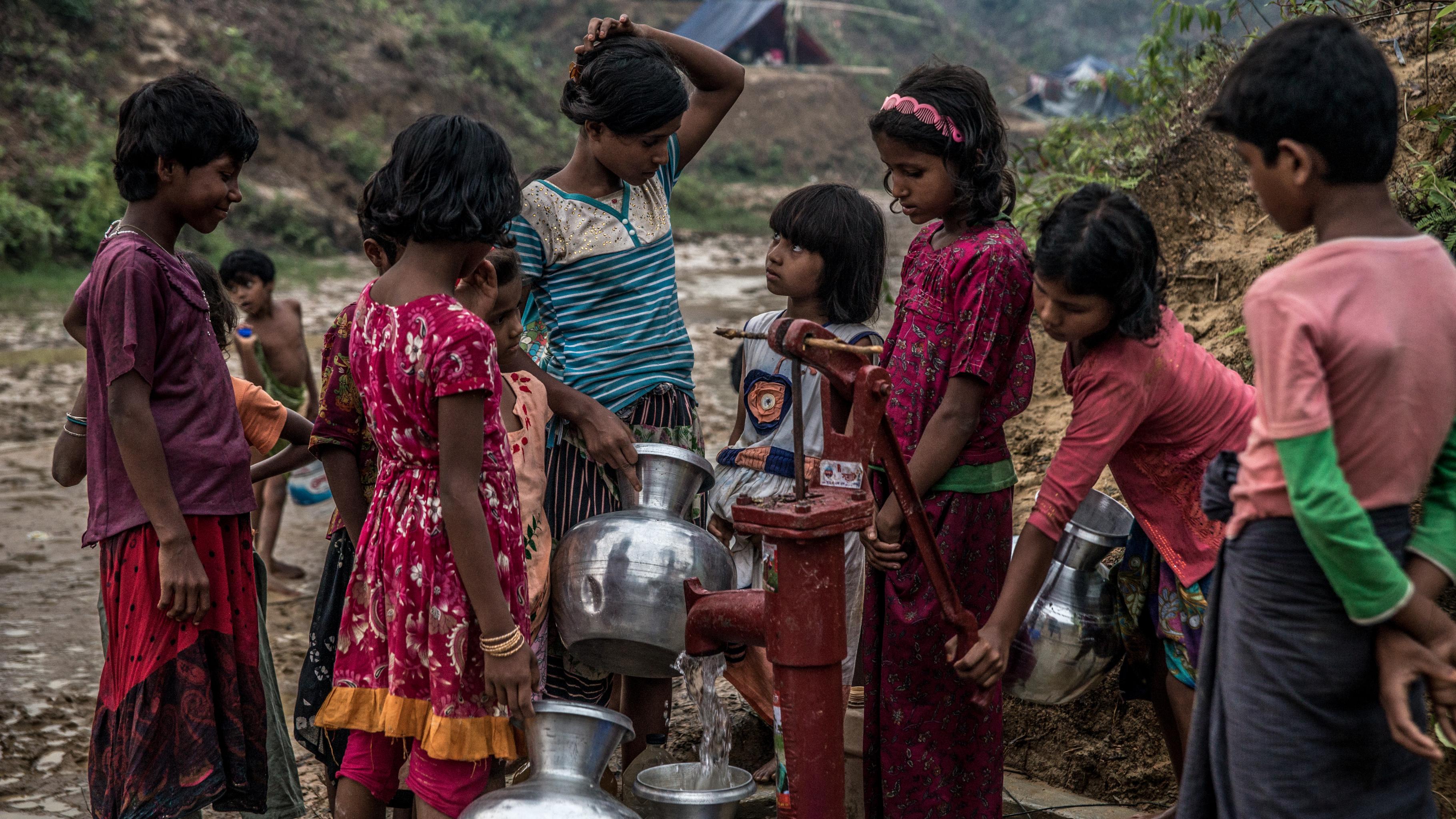 Eine Gruppe von Mädchen füllt an einer Pumpe Wasser in Behälter