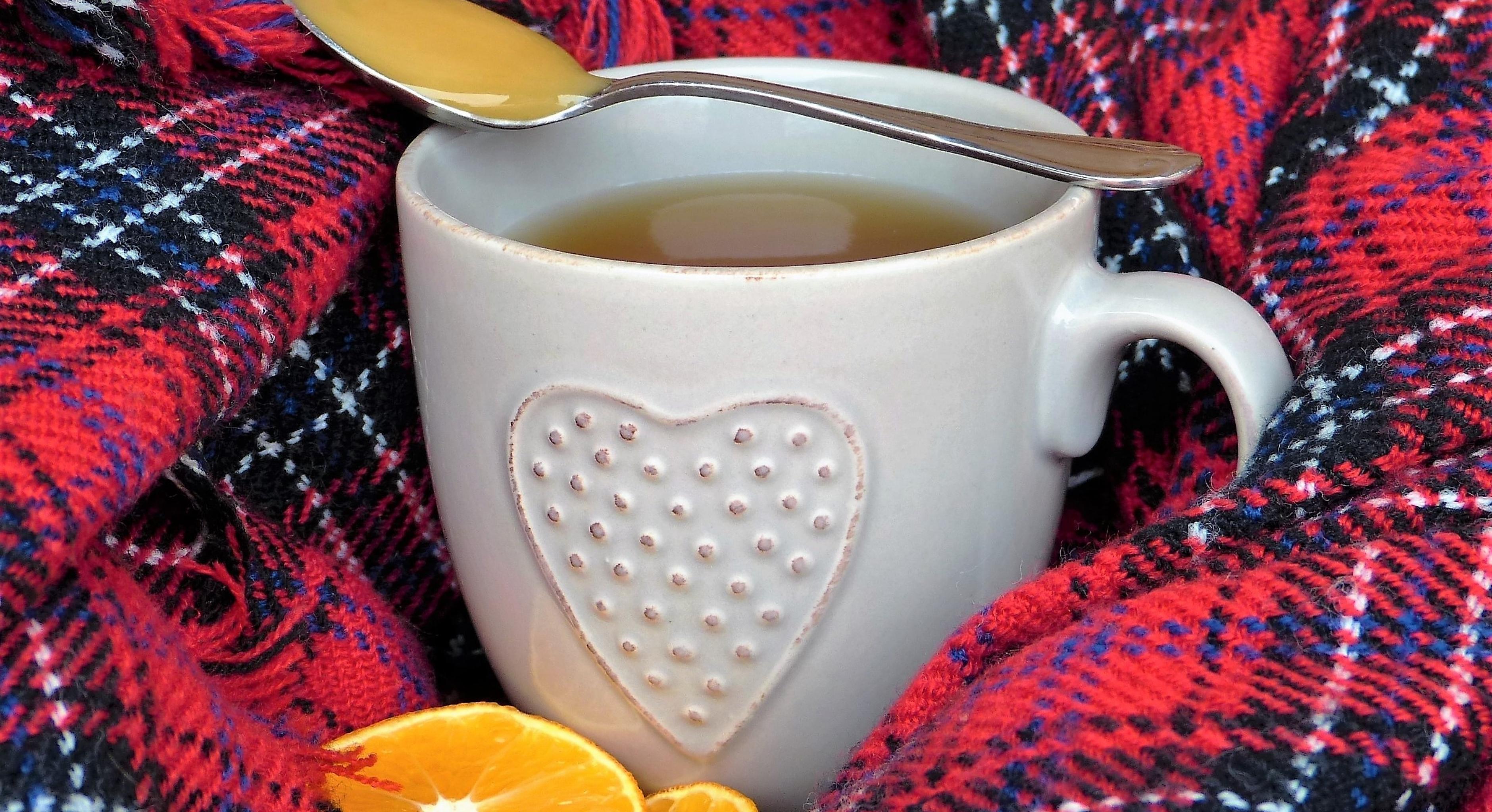 Eine Tasse Tee mit einem Löffel Honig und Orangenscheiben