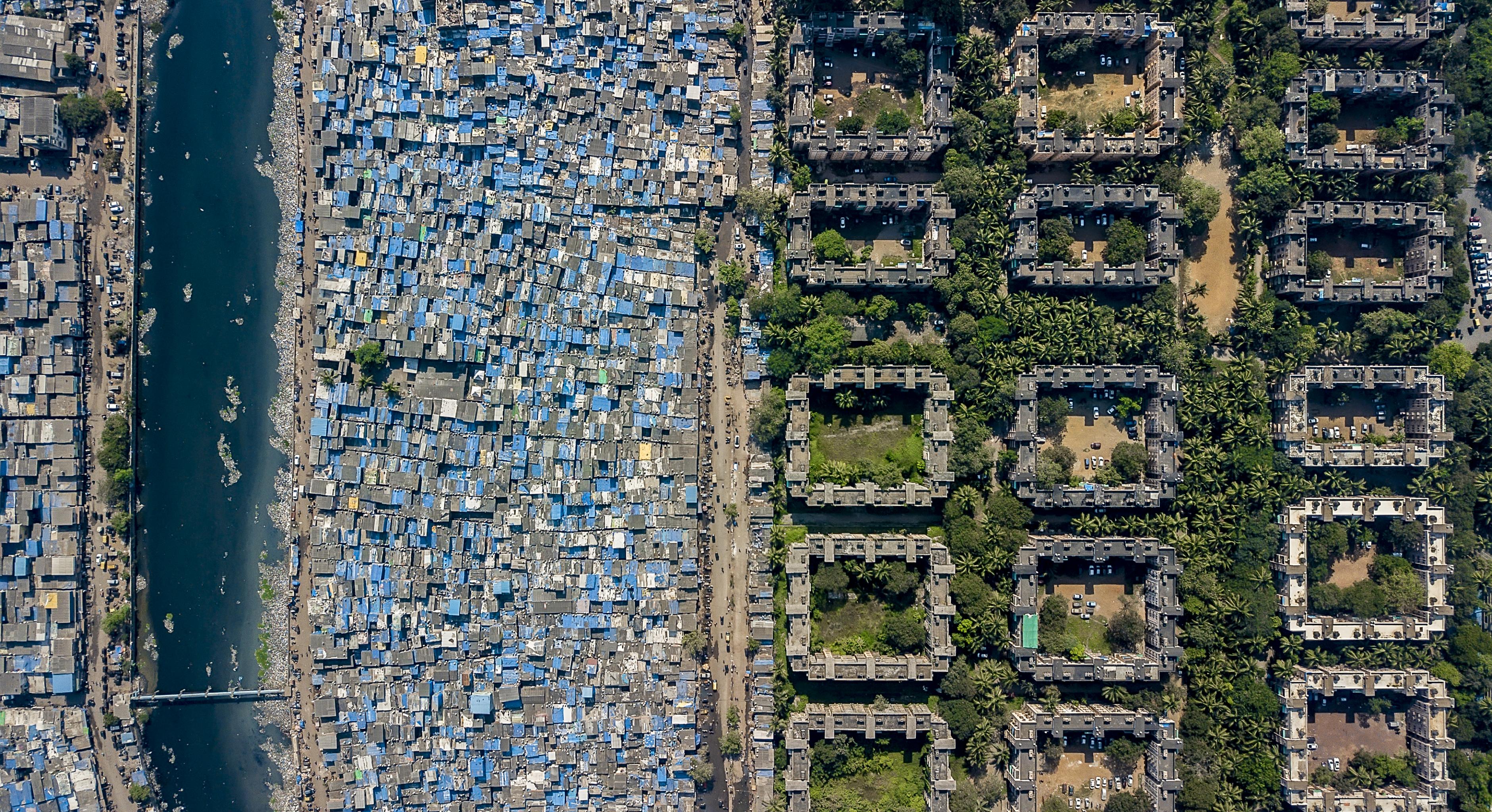 Luftbildaufnahme einer Stadt: Einfache Behausungen auf der einen, Wohnungen Wohlhabender auf der anderen Seite