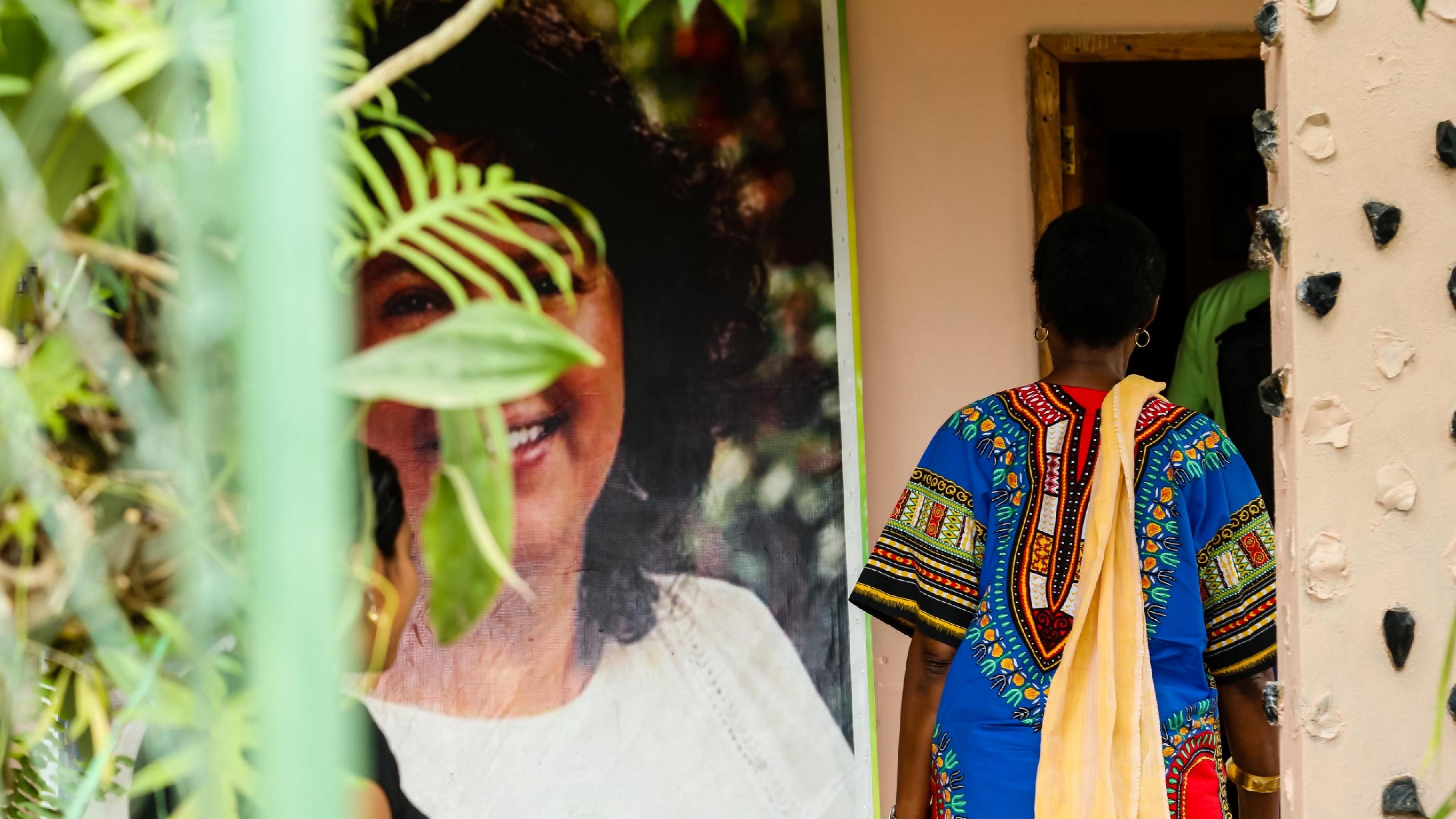 An einem großen Portraifoto von Berta Cáceres im Innenhof vorbei geht Winnie Byanyima ins Haus