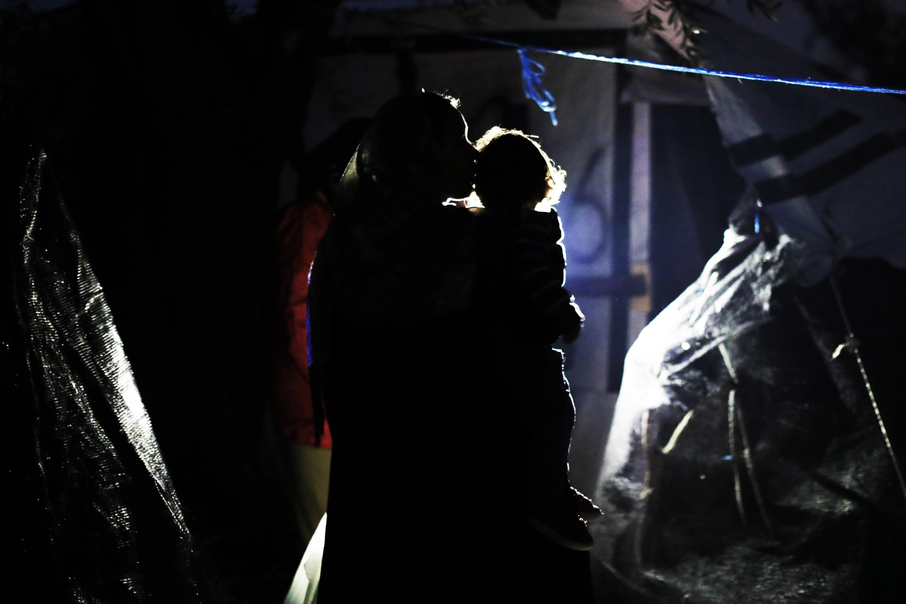 Eine Frau trägt ihr Kind in einem Flüchtlingscamp