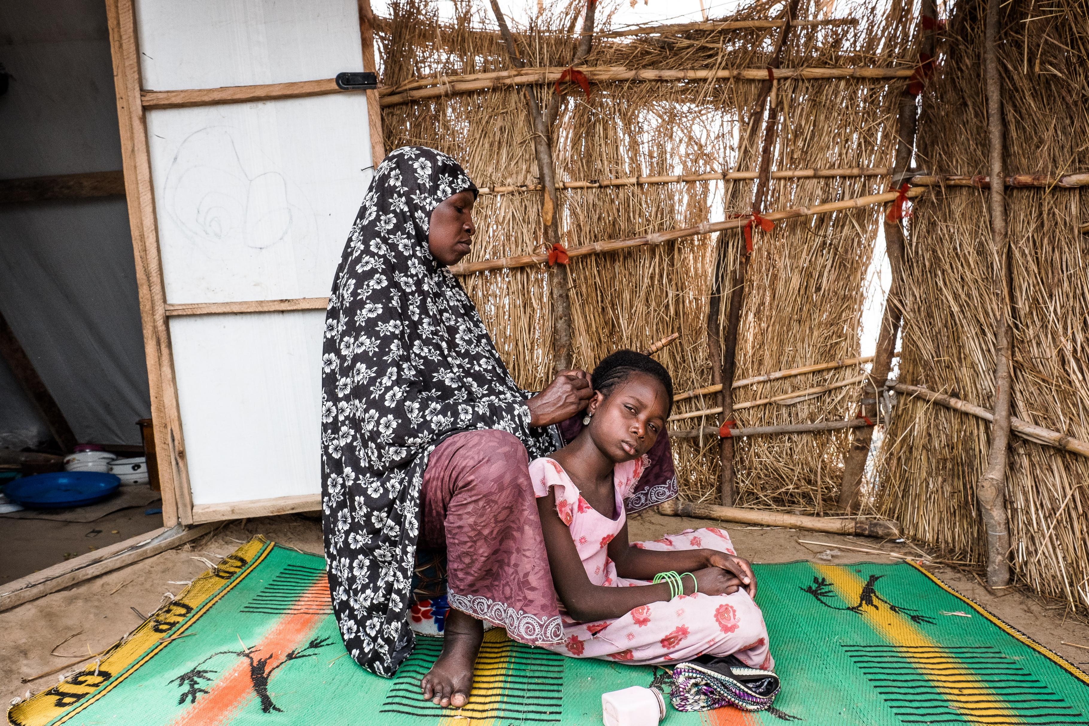 Hassana flechtet die Haare ihrer Tochter in einem Camp in Damboa in Nigeria