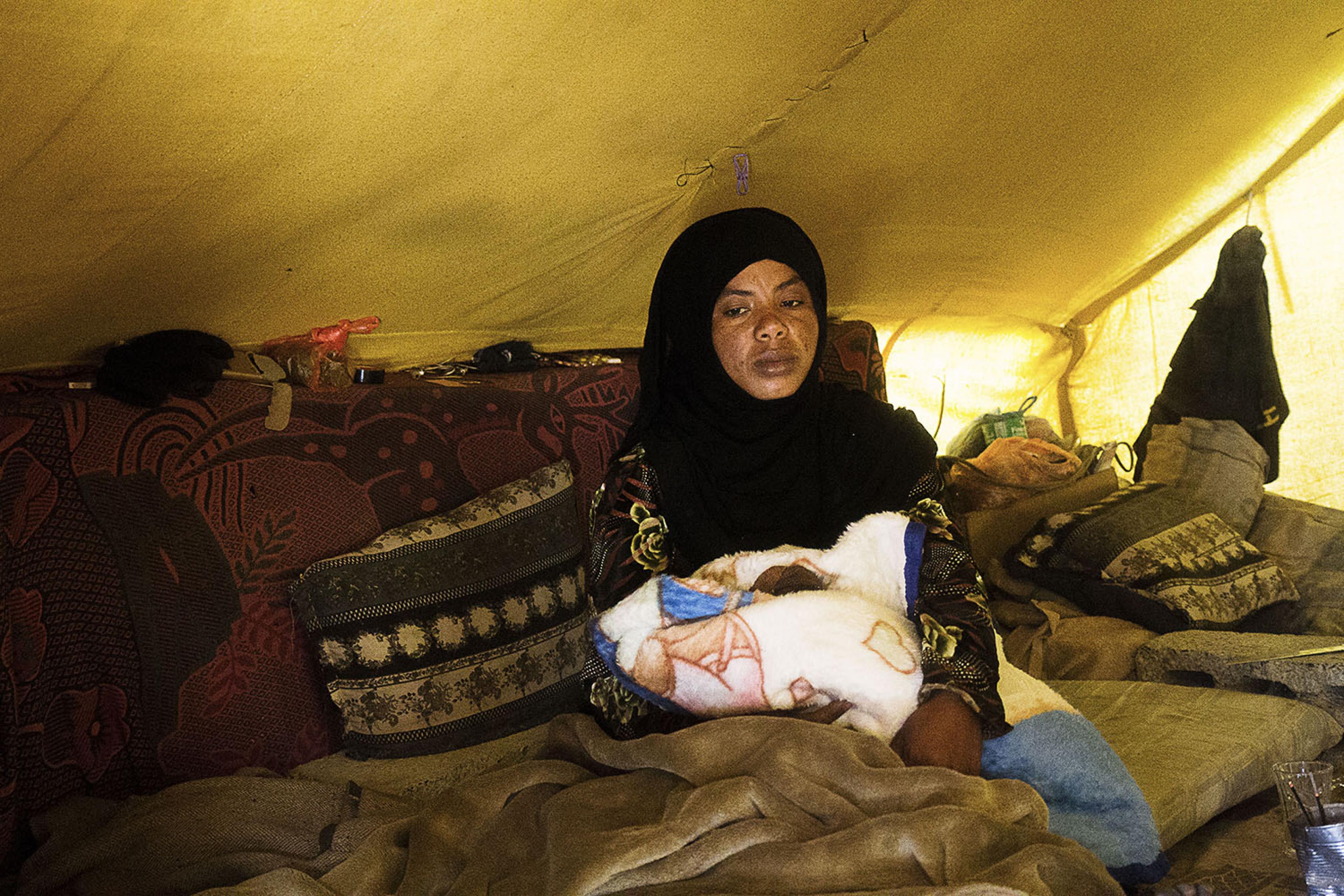 Hafsa sitzt mit ihrem Neugeborenen in einem Zelt