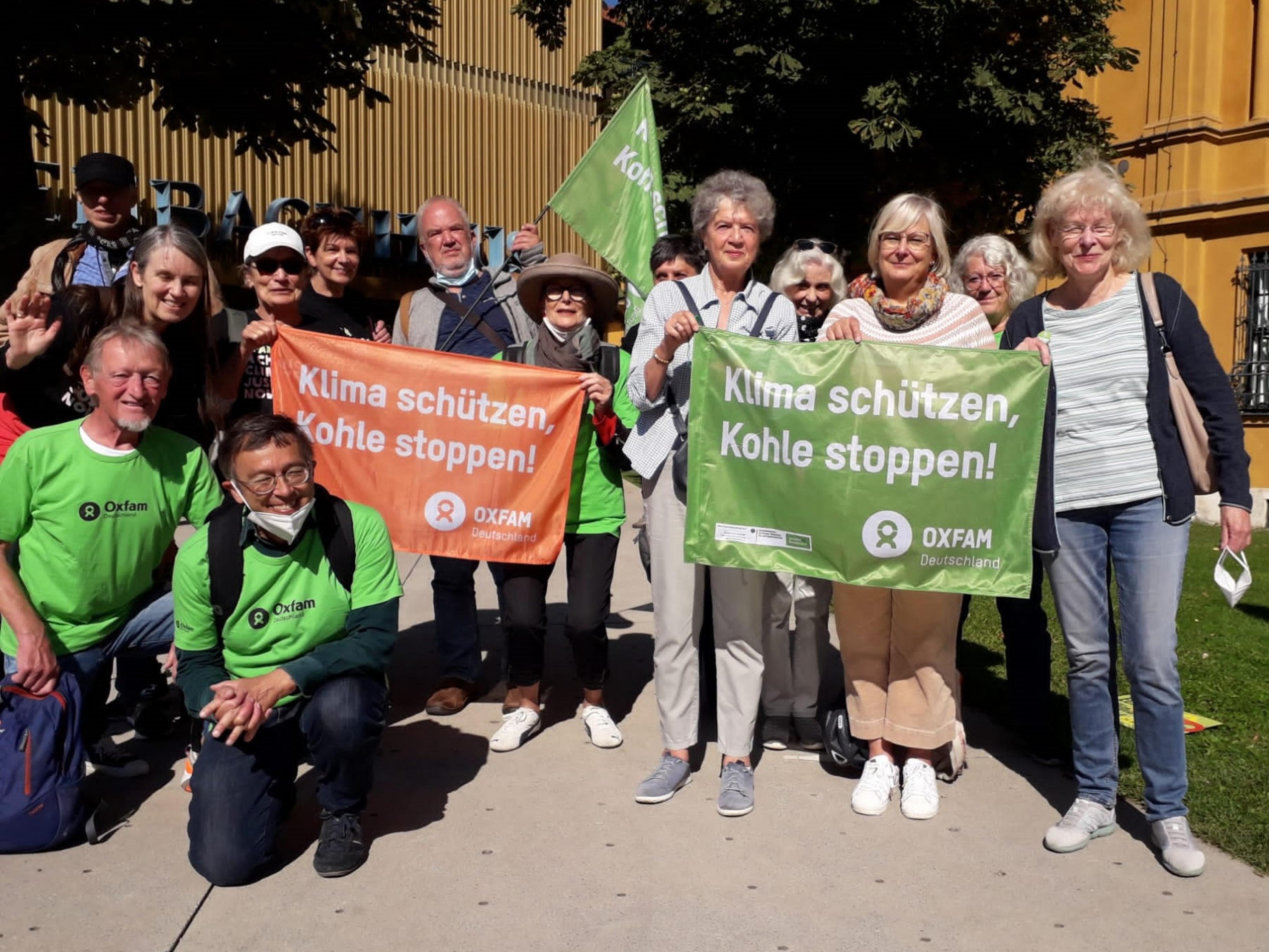 14 Personen, Freiwillige der Münchener Oxfam Shops, halten beim Klimastreik am 24.09.2021 in München Fahnen mit der Aufschrift „Klima schützen, Kohle stoppen!“