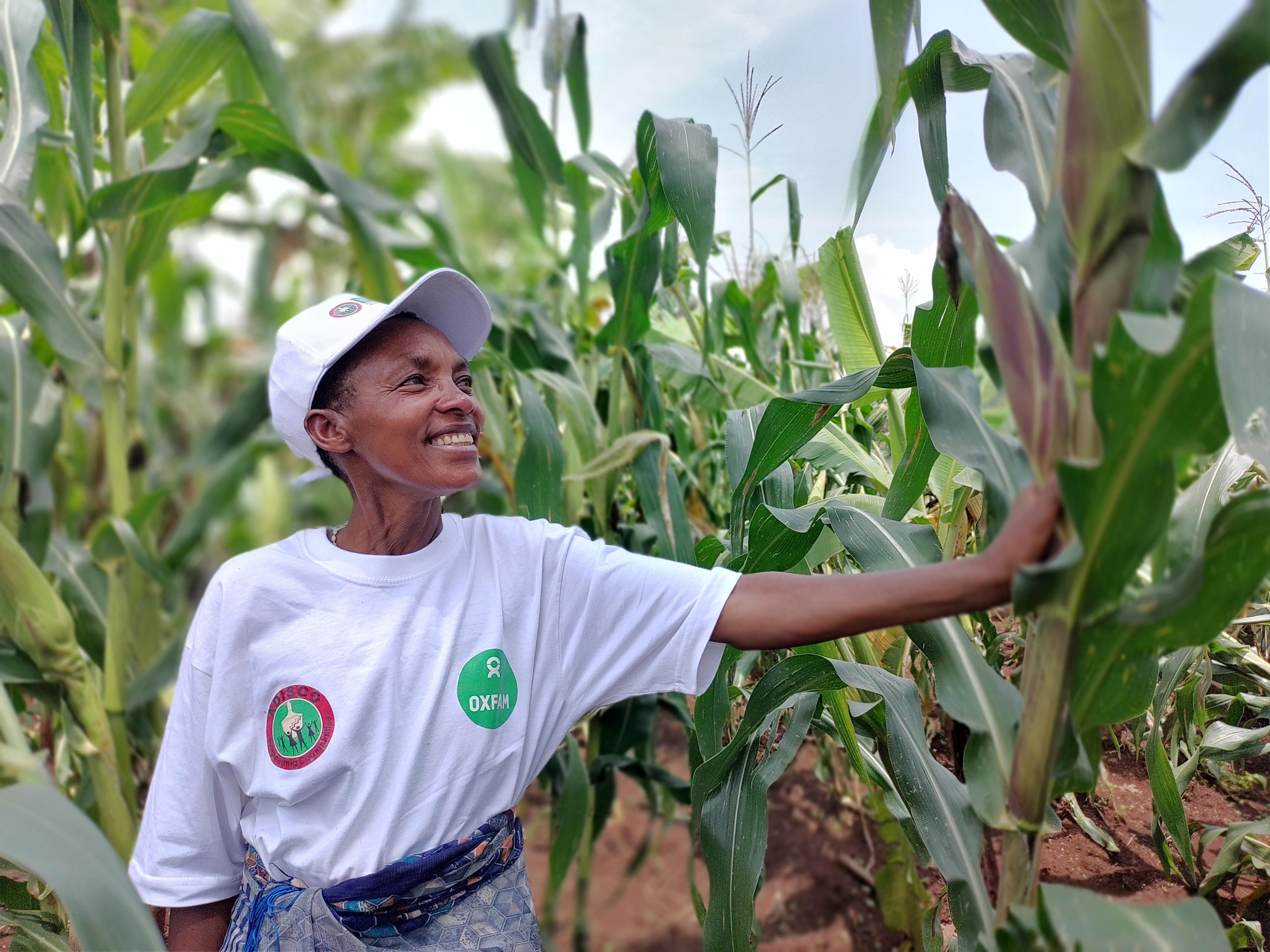 Clémence Nibaruta steht stolz in ihrem Maisfeld in Gitega, Burundi. Sie hat an Schulungen unserer Partnerorganisation ADISCO in Gitega (Burundi) teilgenommen und betreibt nun agrarökologischen Landbau.