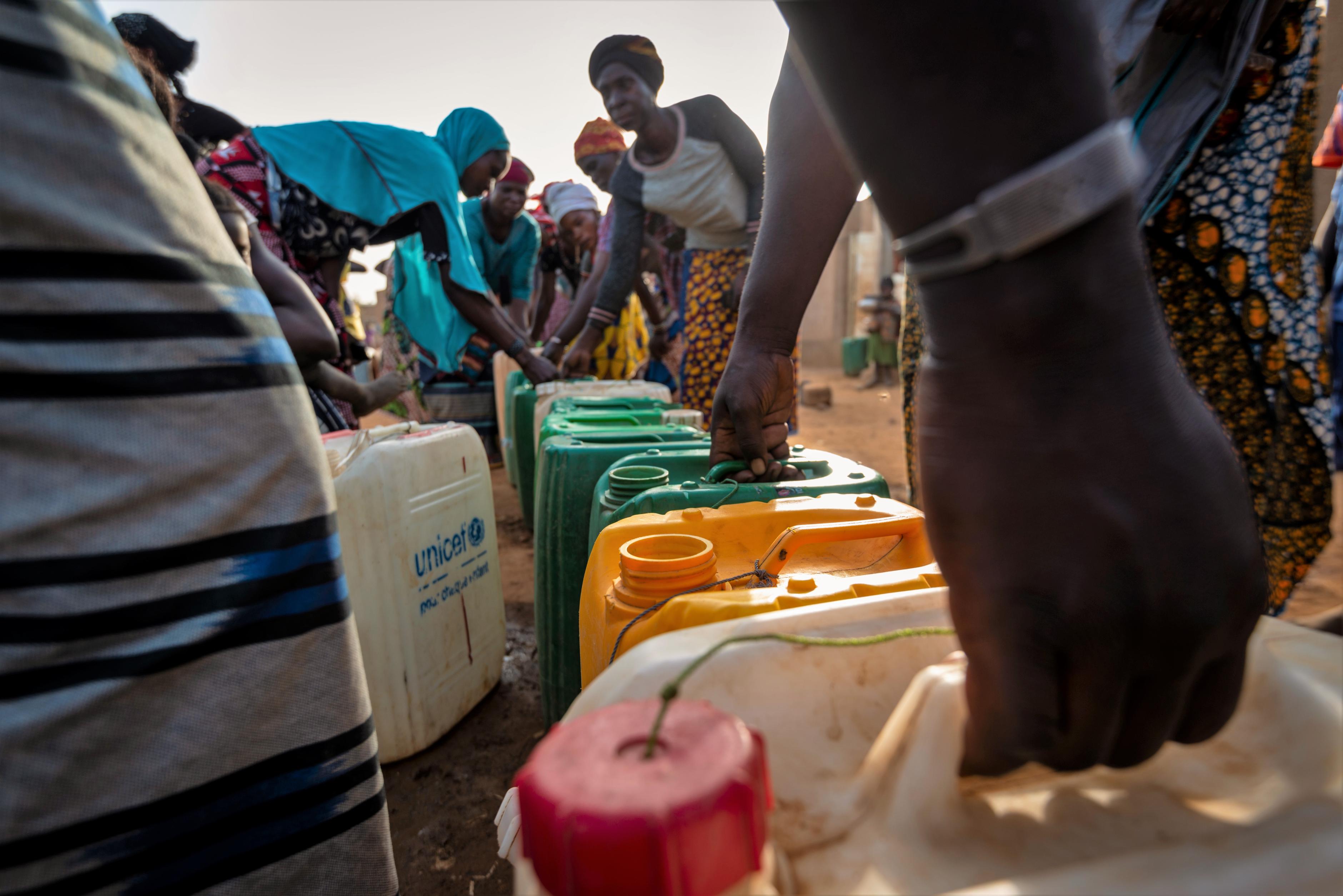 Eine Gruppe von Menschen greift nach Wasserkanistern in Kaya, Burkina Faso.