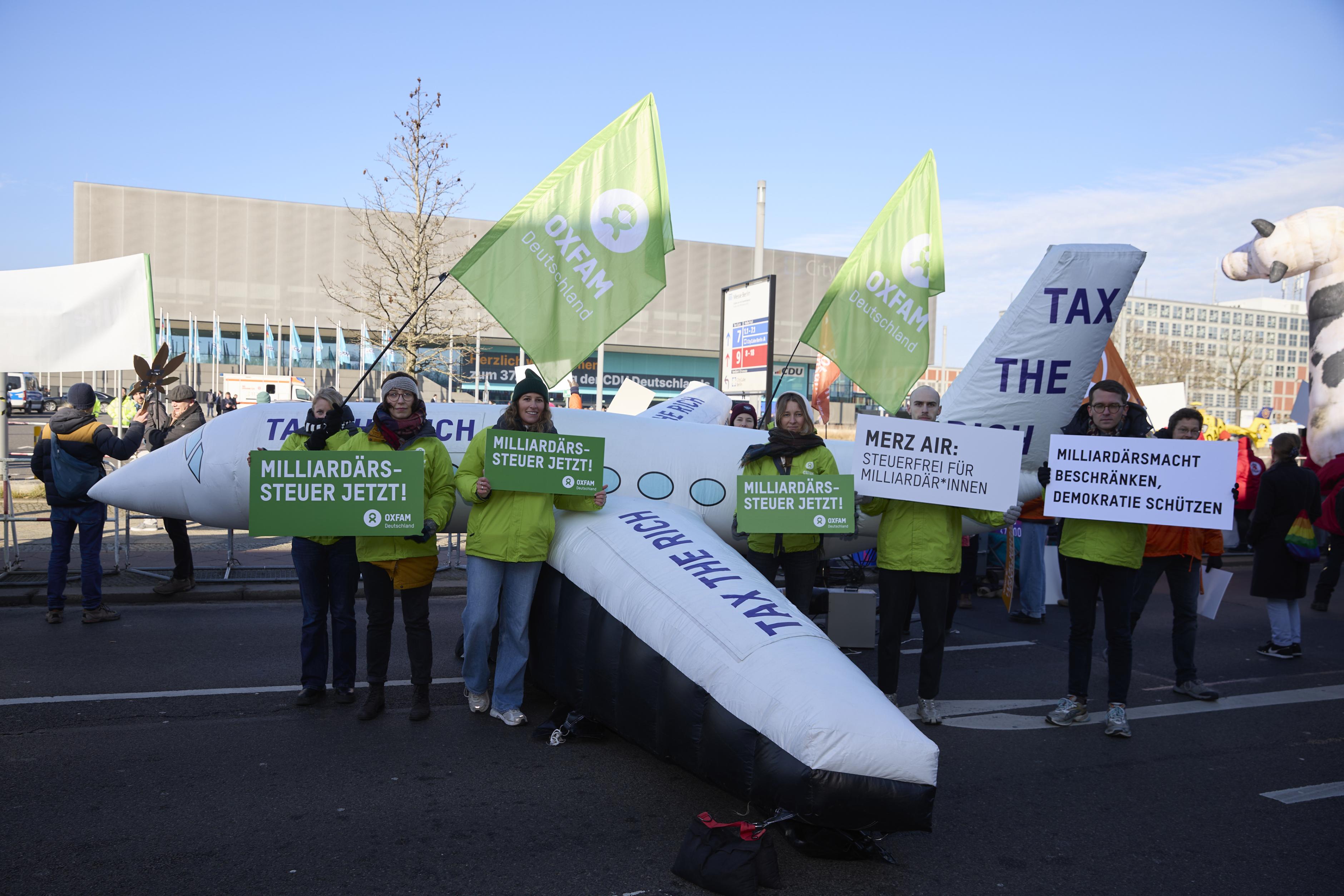 Demonstrierende mit einem aufblasbaren Flugzeit mit der Aufschrift "Tax the Rich" ("Besteuert die Reichen")