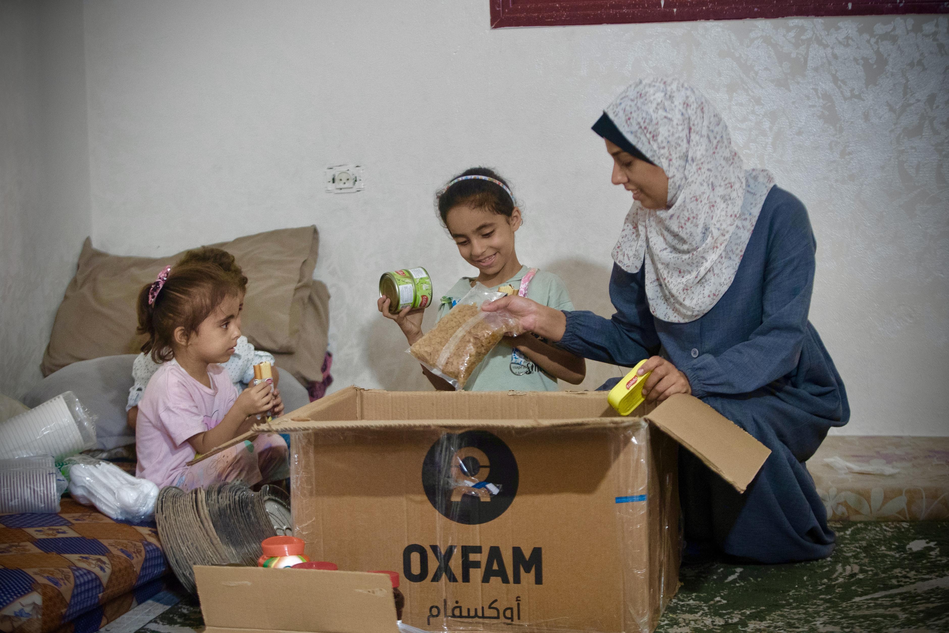 Eine Familie im Gazastreifen öffnet eine Lebensmittelpaket mit Trockenlebensmitteln.