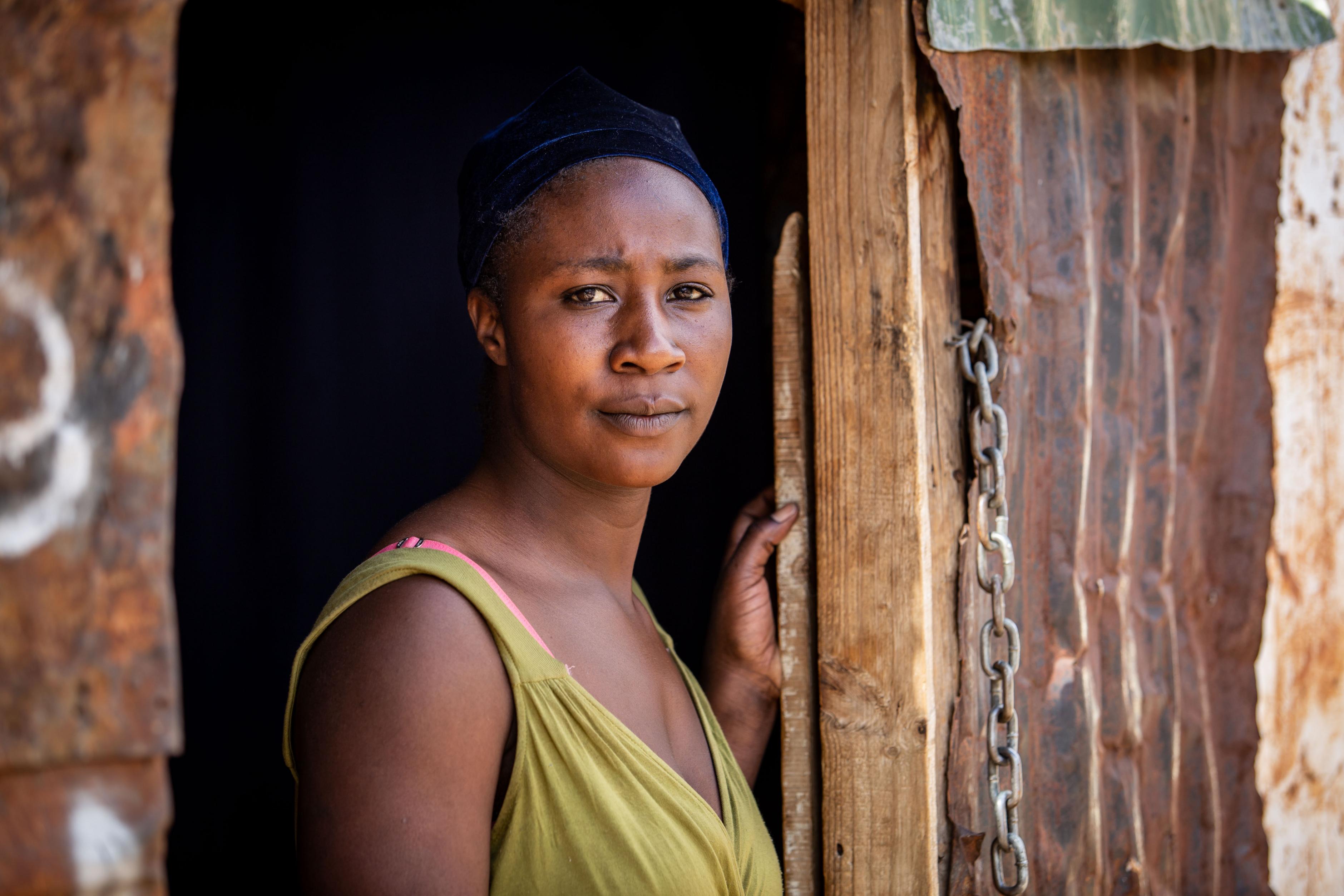 Eine Frau steht in einer Tür und schaut mit ernstem Blick direkt in die Kamera. Primrose Mulenga ist 25 und stammt aus Simbabwe. Nach Südafrika kam sie in der Hoffnung, hier mehr Geld zu verdienen. 
