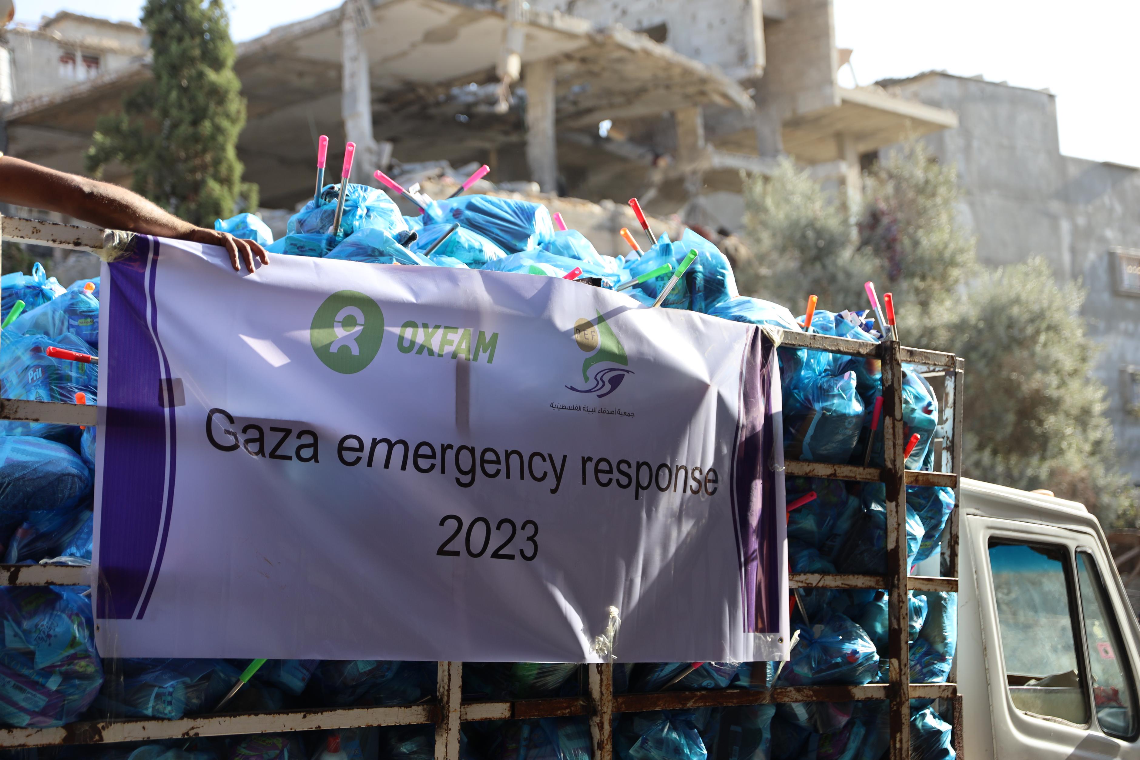 Ein kleiner Lastwagen ist beladen mit blauen Tüten. Auf einem Banner steht "Gaza emergency response"