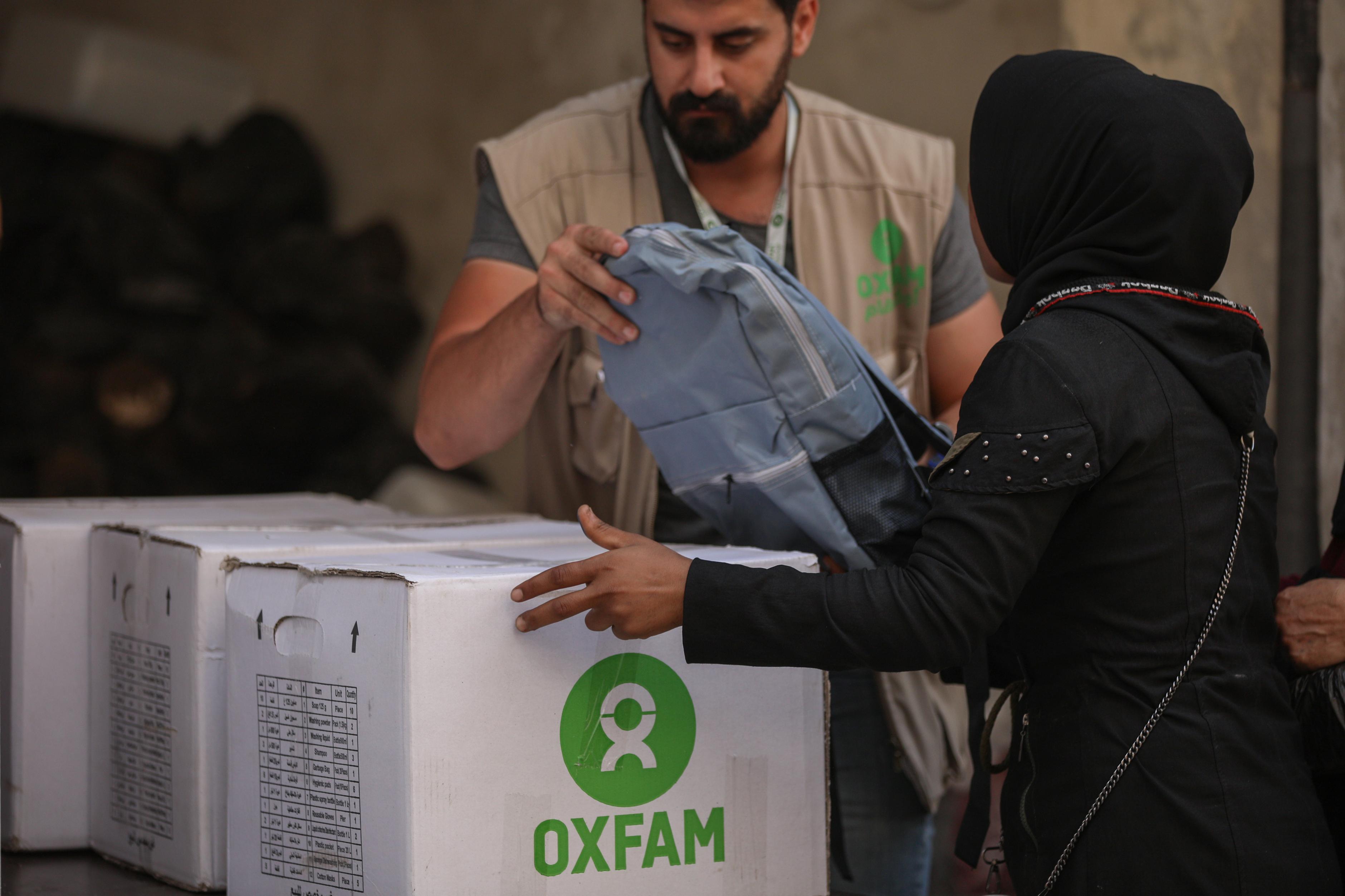 Ein Mann und eine Frau unterhlaten sich. Ein Karton auf dem Oxfam steht wird dabei übergeben.