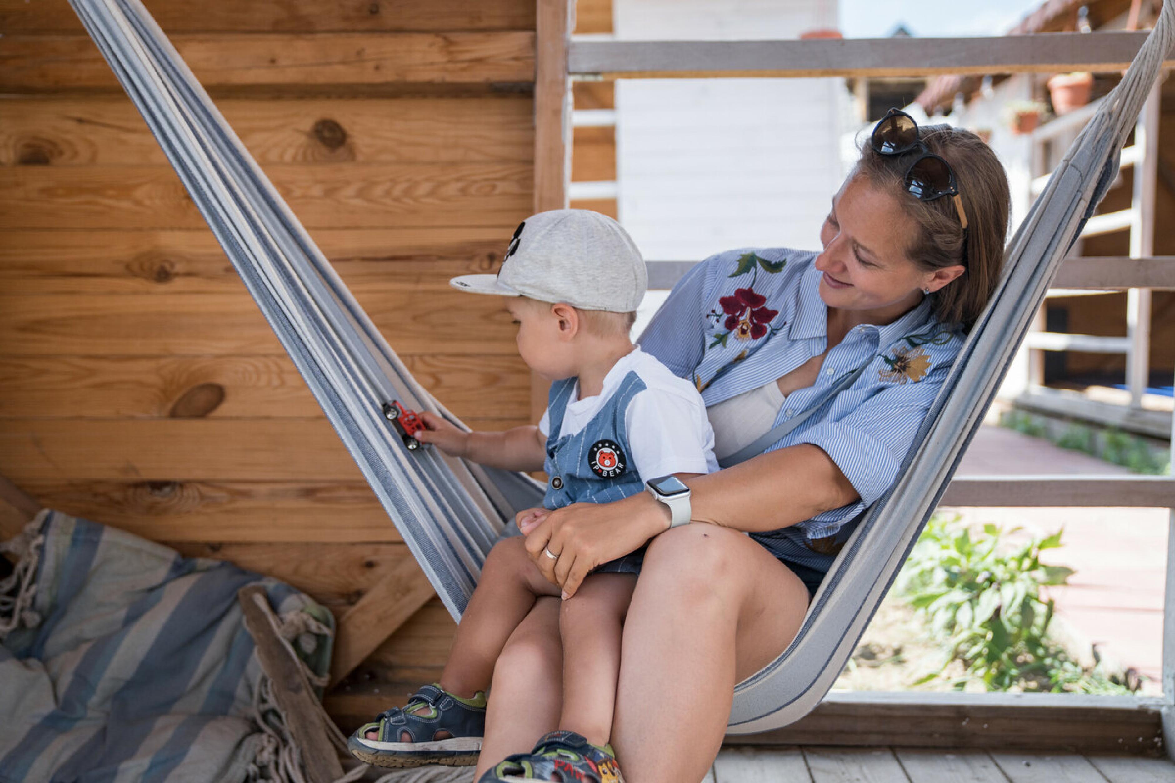 Katerina*, eine Geflüchtete aus der Ukraine, zusammen mit ihrem Sohn Miron*. Sie sitzen in einer Hängematte in einem Spielhaus und wirken ganz entspannt.