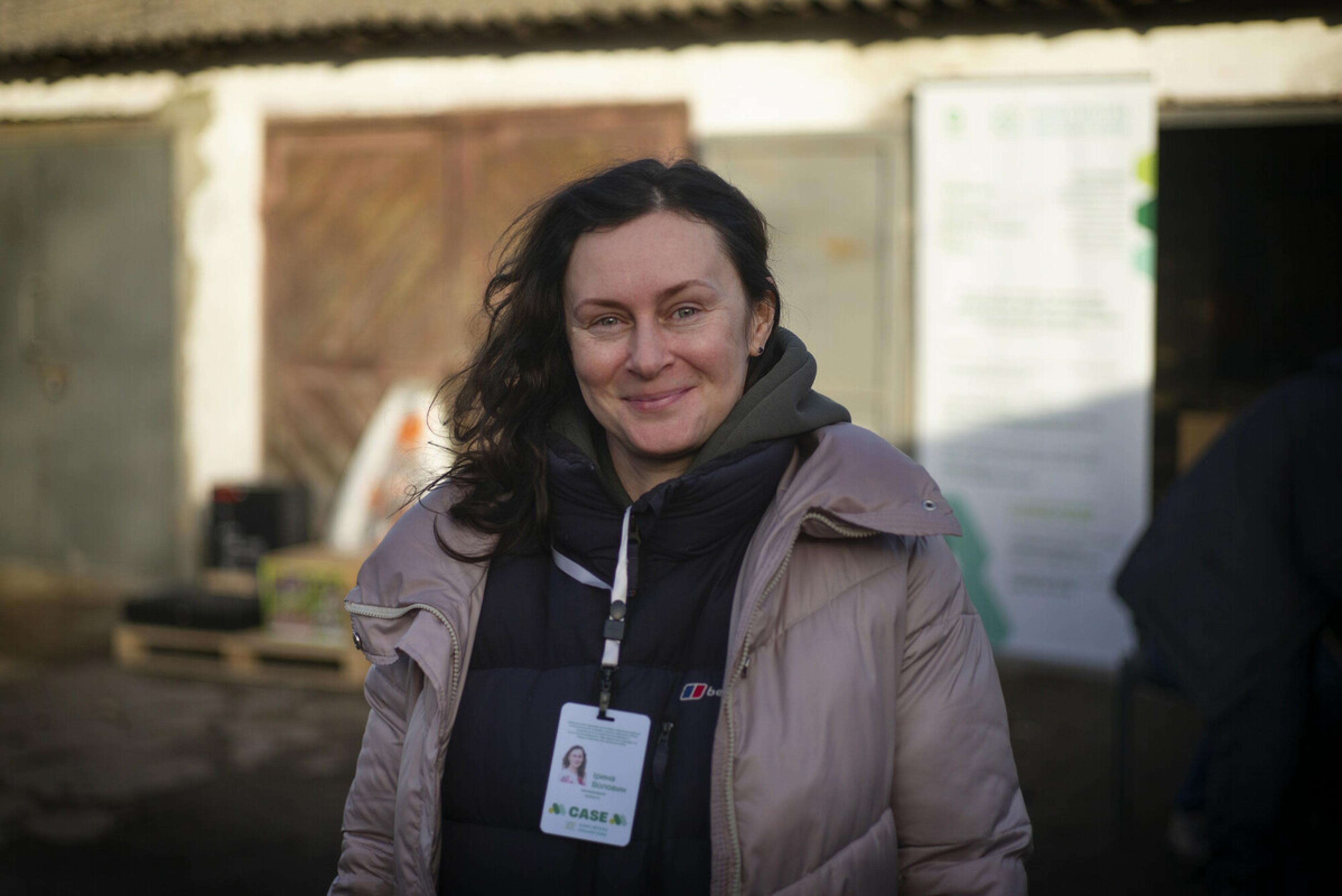 Irina Volovyk lächelt freundlich in die Kamera. Sie steht vor einer Garage oder einem Stall.