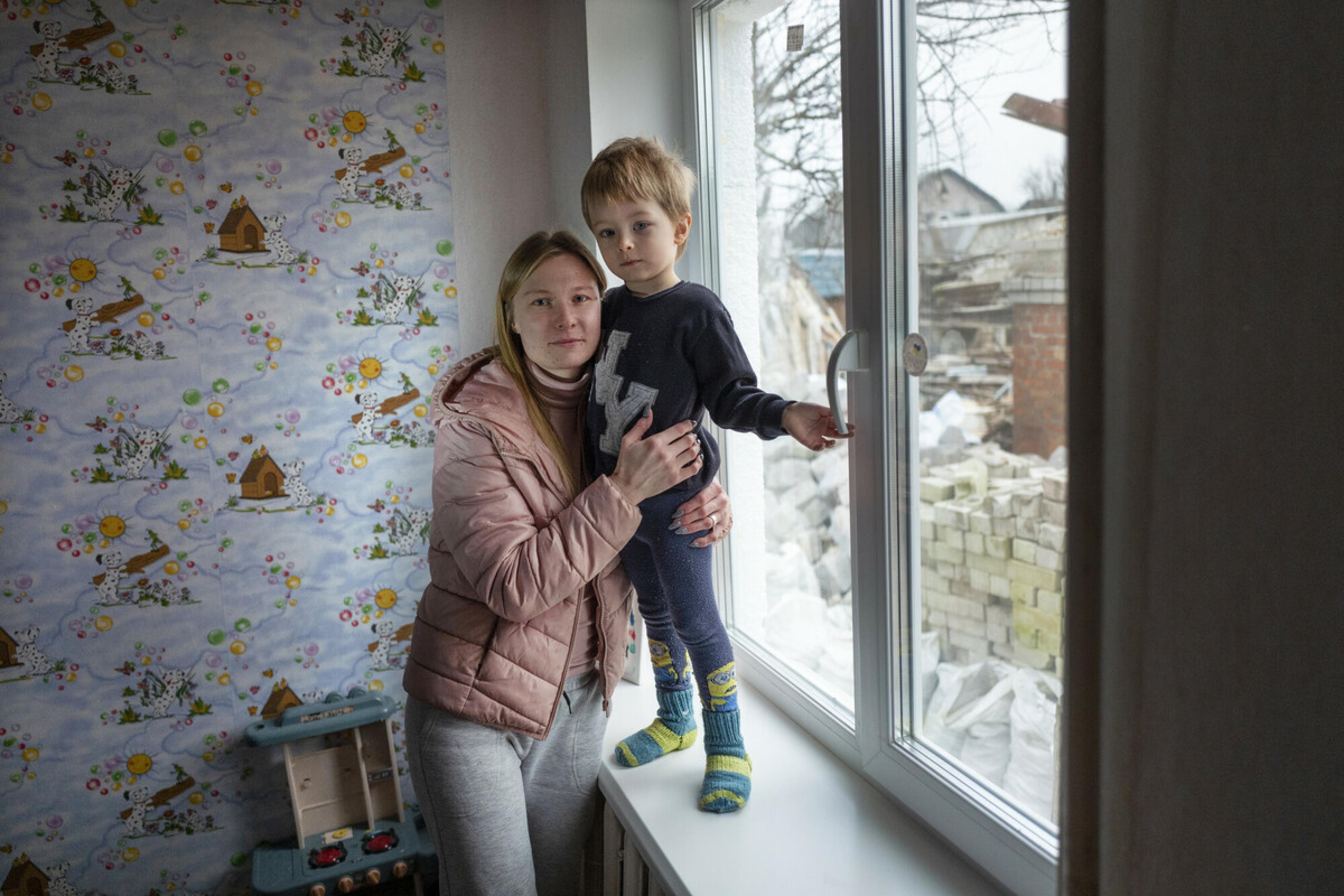 Ana Gendmalo und ihr Sohn Serhiy stehen vor einem neu eingebauten Fenster im Kinderzimmer. Sie schauen ernst in die Kamera.