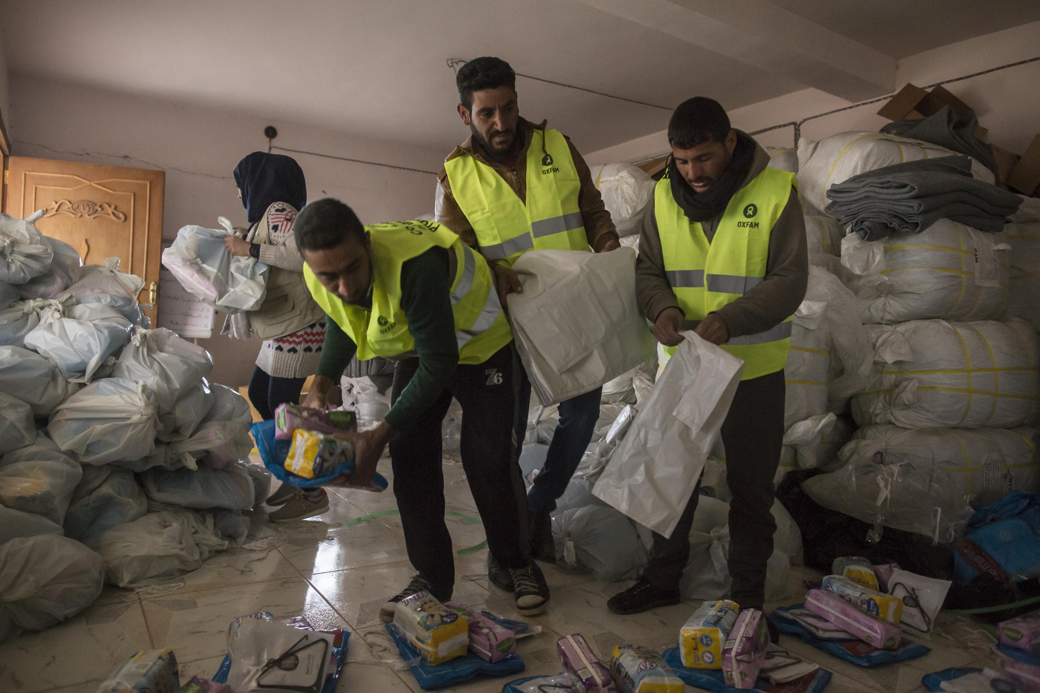Drei Männder packen verschiedene Hilfsgüter in einem Plastiksack