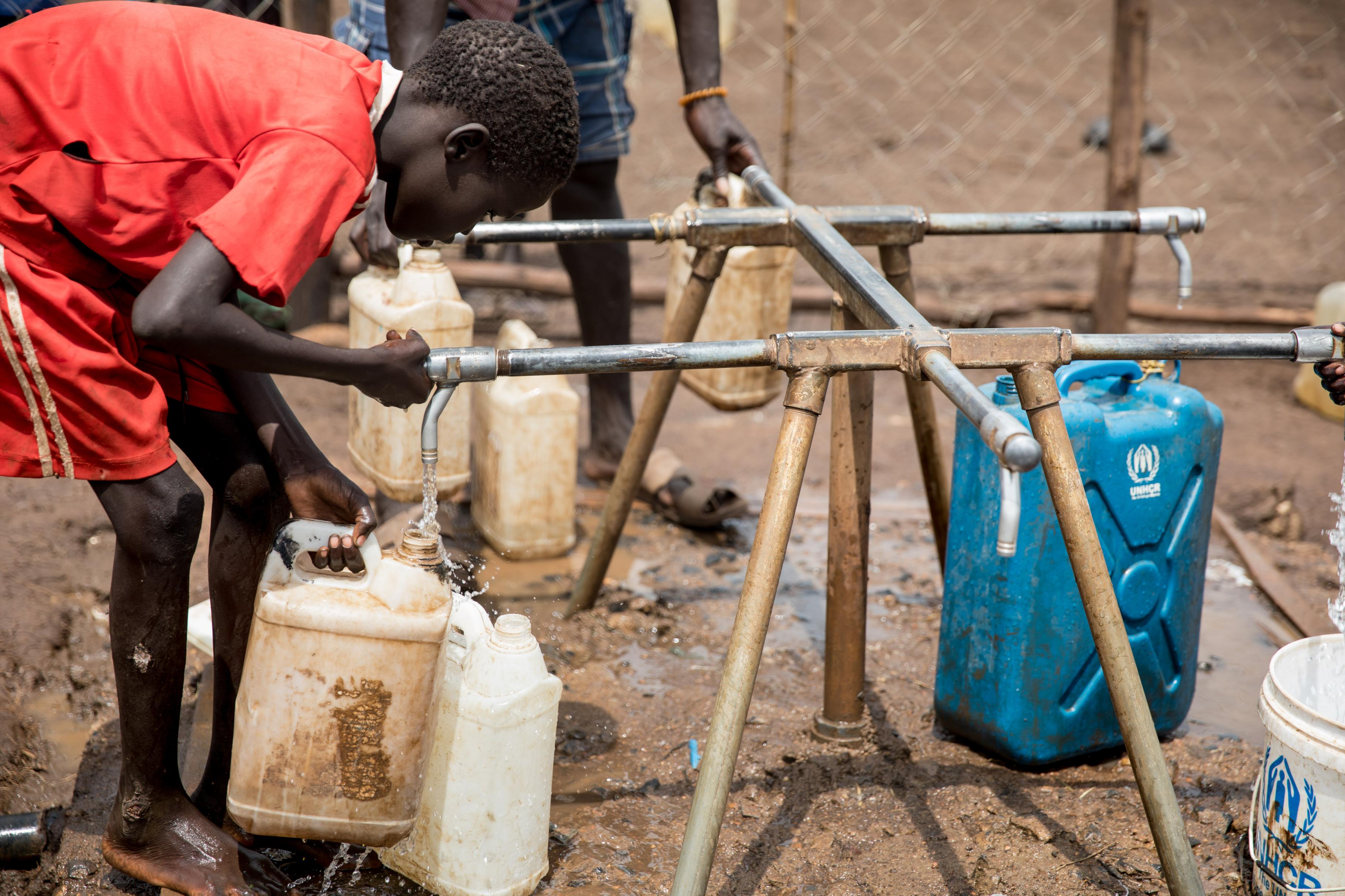 Ein Junge, der im Nguenyyiel Flüchtlingscamp lebt, füllt einen Kanister mit sauberem Wasser. 
