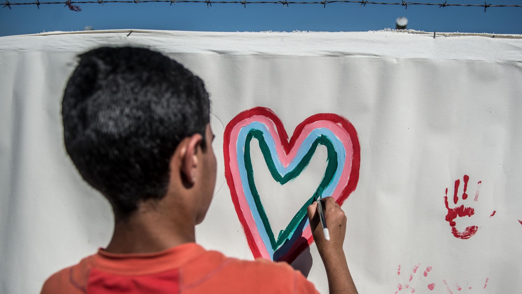 Ein irakischer Junge malt ein Herz auf eine Leinwand