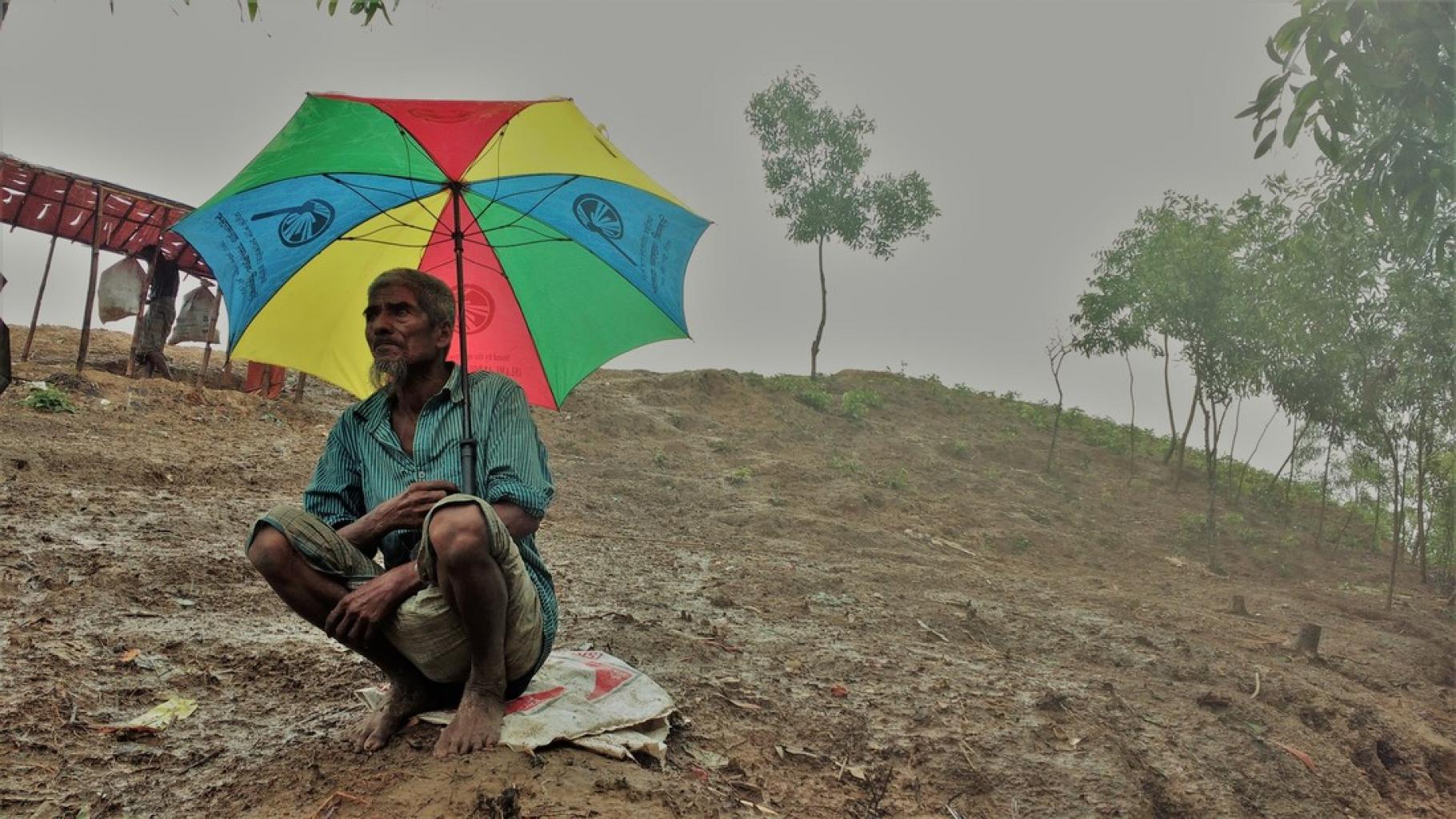 Rohingya-Mann mit Regenschirm auf Hügel