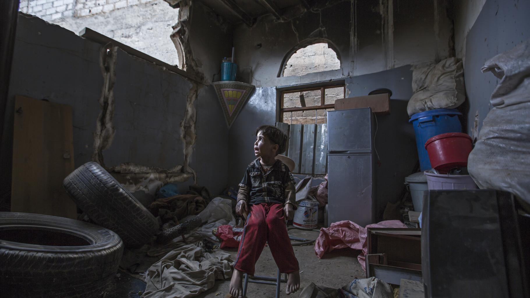Ein Kind sitzt in seinem Zuhause, das durch einen Luftangriff zerstört wurde