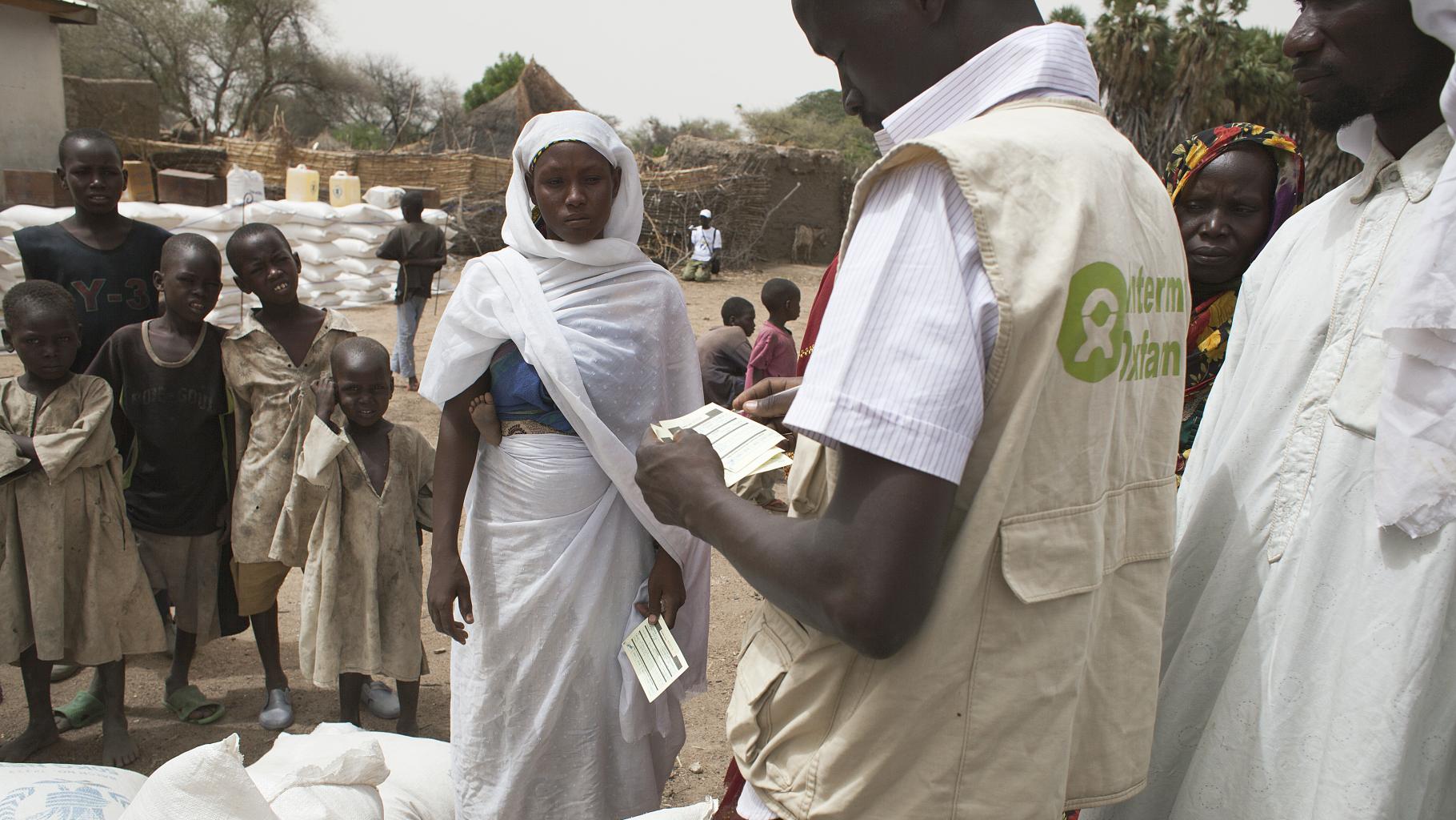 Eine junge Mutter und ein Oxfam-Mitarbeiter bei der Nahrungsmittelausgabe