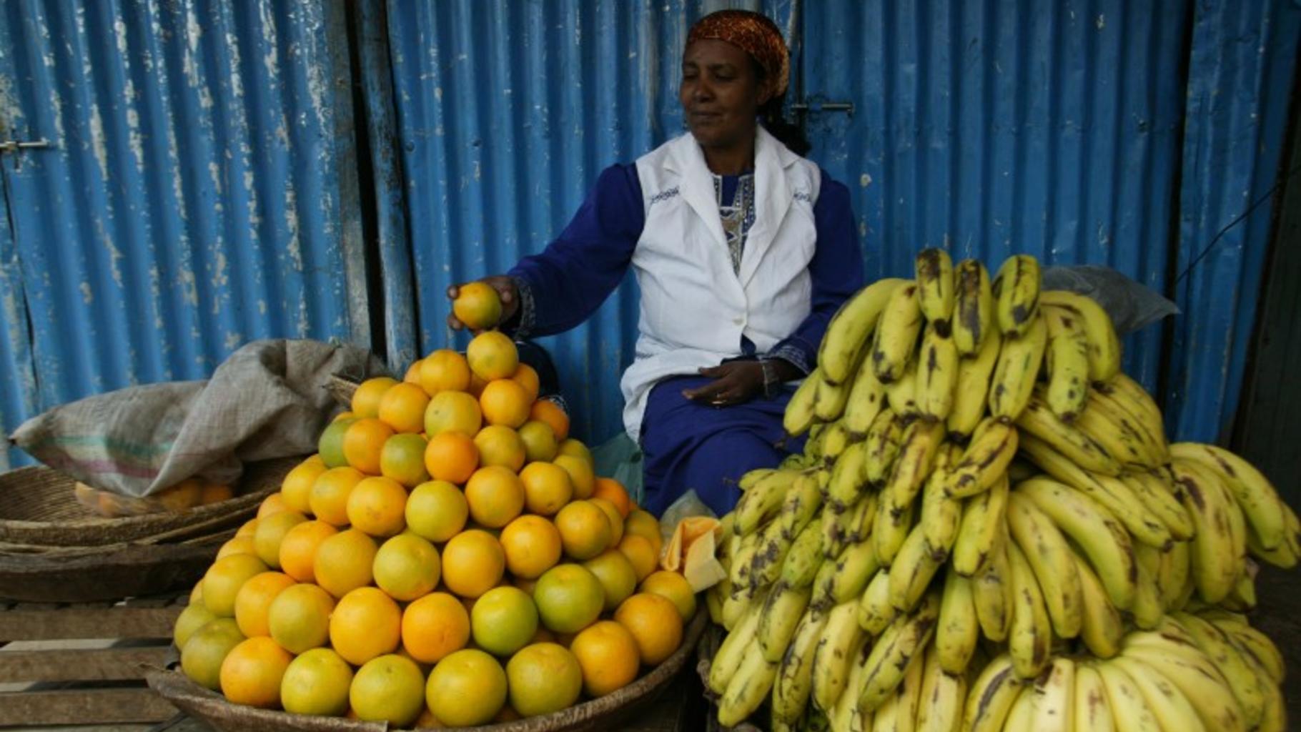 Eine Frau verkauft Bananen und Orangen auf einem Markt in Äthiopien