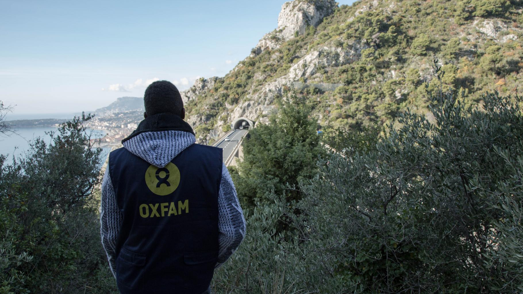 Oxfam-Mitarbeiter Adoum Ismail steht an der Grenze zu Frankreich und Italien und betrachtet eine Autobahnbrücke..