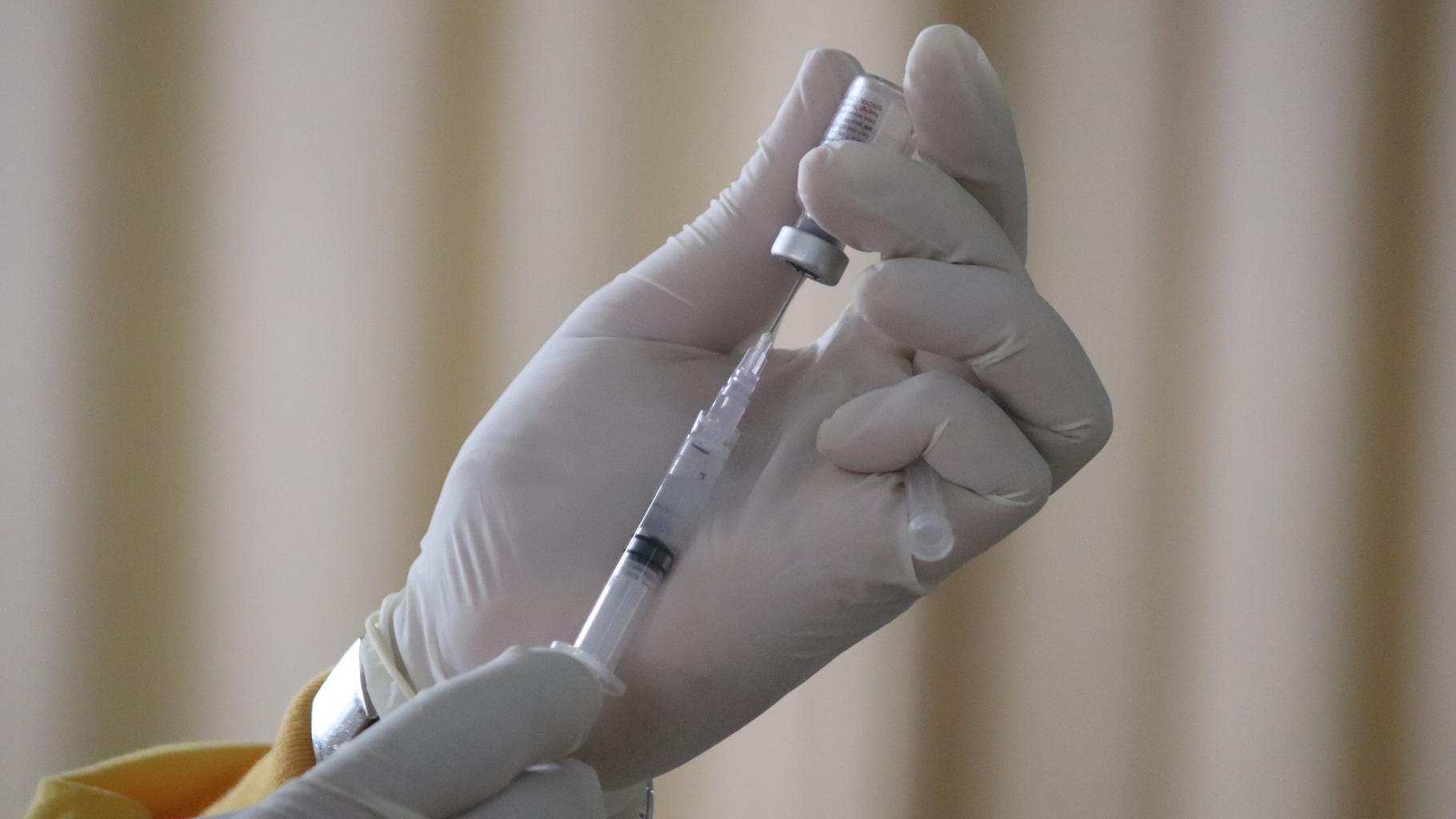 Eine Person zieht eine Spritze mit Impfstoff auf