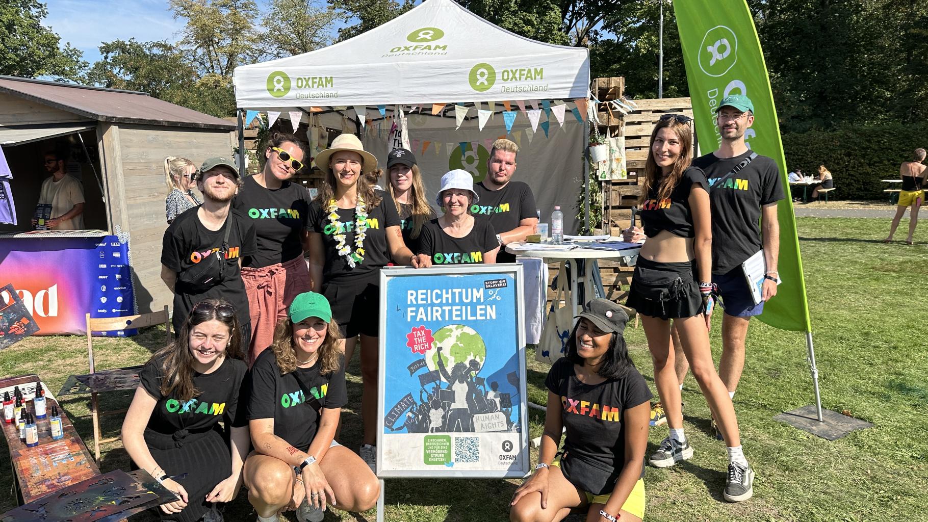 Eine Gruppe von Menschen steht vor einem Festivalstand von Oxfam