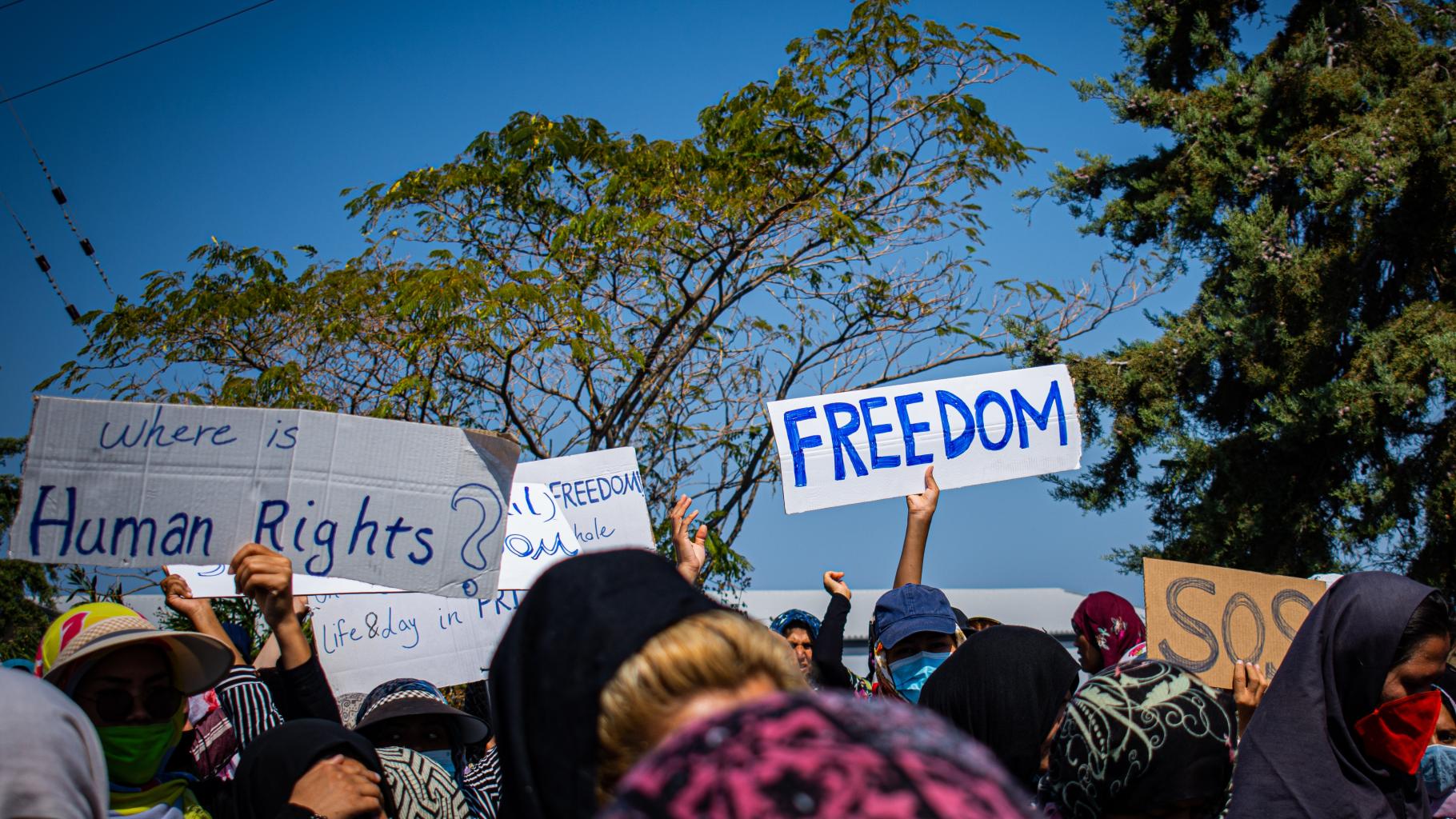 Protestierende Menschen halten Schilder hoch mit der Aufschrift "Freedom" und "Where is Human Rights?"