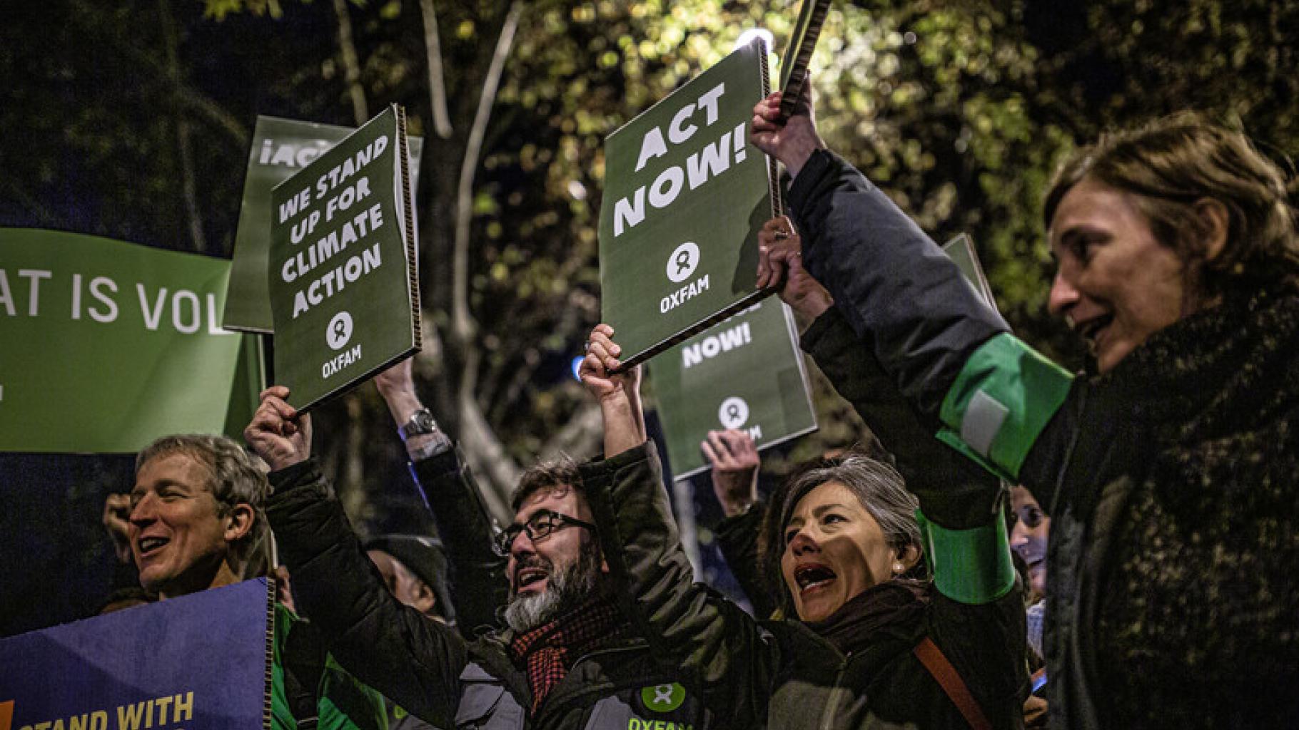 Menschen auf dem Klimaprotest in Madrid halten Schilder hoch, auf denen sie fordern jetzt zu handeln