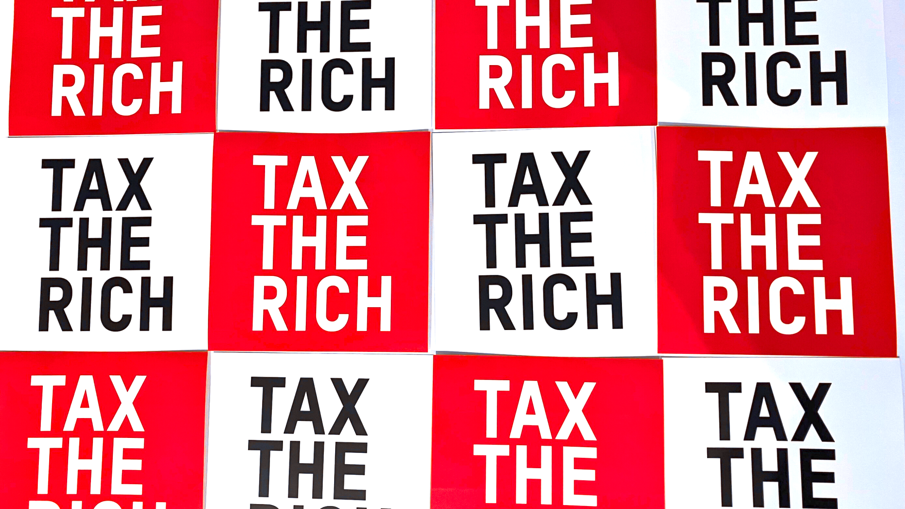 Ein Bild mit der Aufschrift "Tax the Rich" auf einem Schachmuster in rot und weiß.